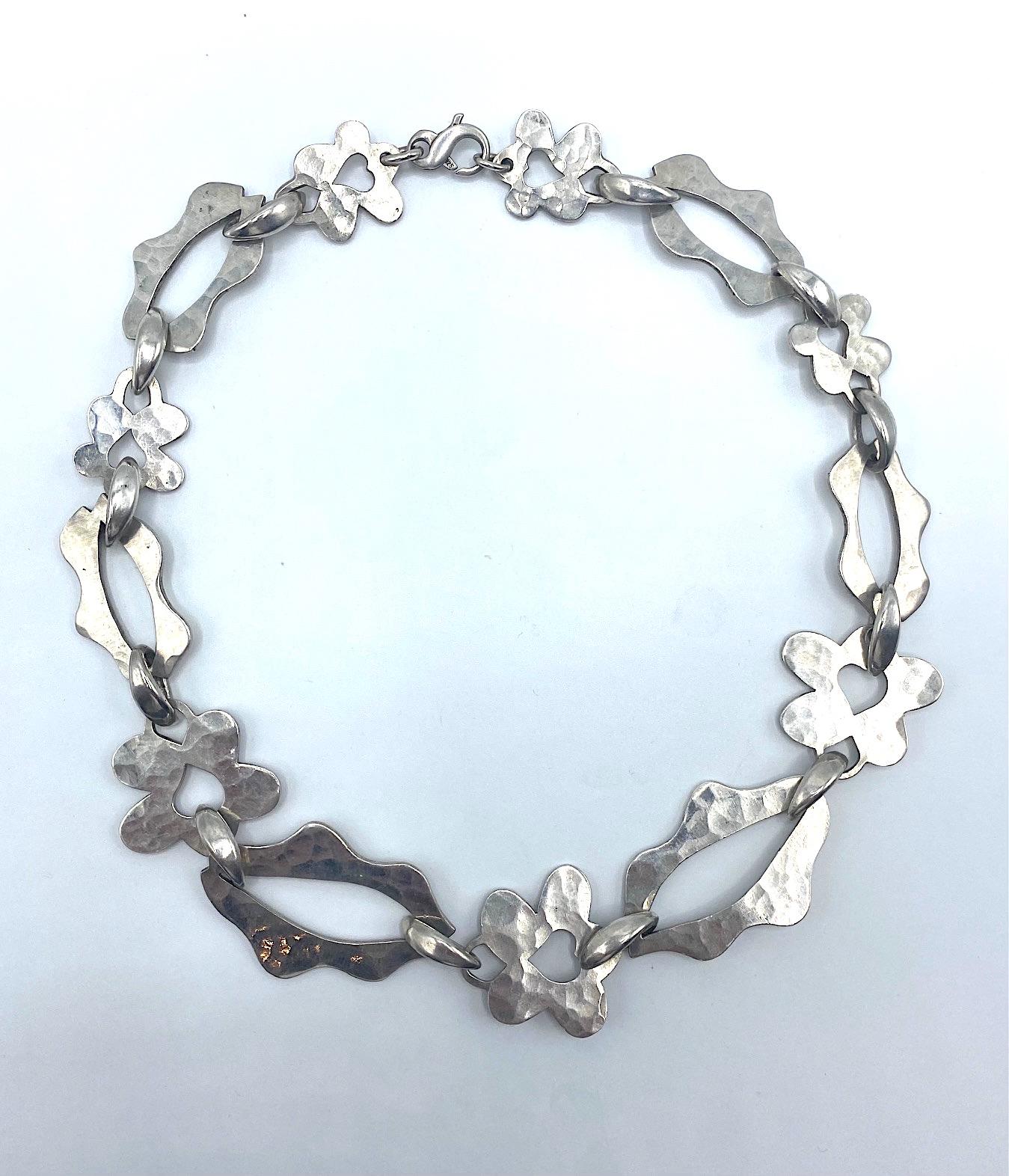 Presented is a 1990s modernist abstract sterling silver necklace by jewelry Dennis Higgins. Each link is carefully hand made with a martele' or hammered finish on the front and a smooth back. Additionally, the  connector links are all hand made .The