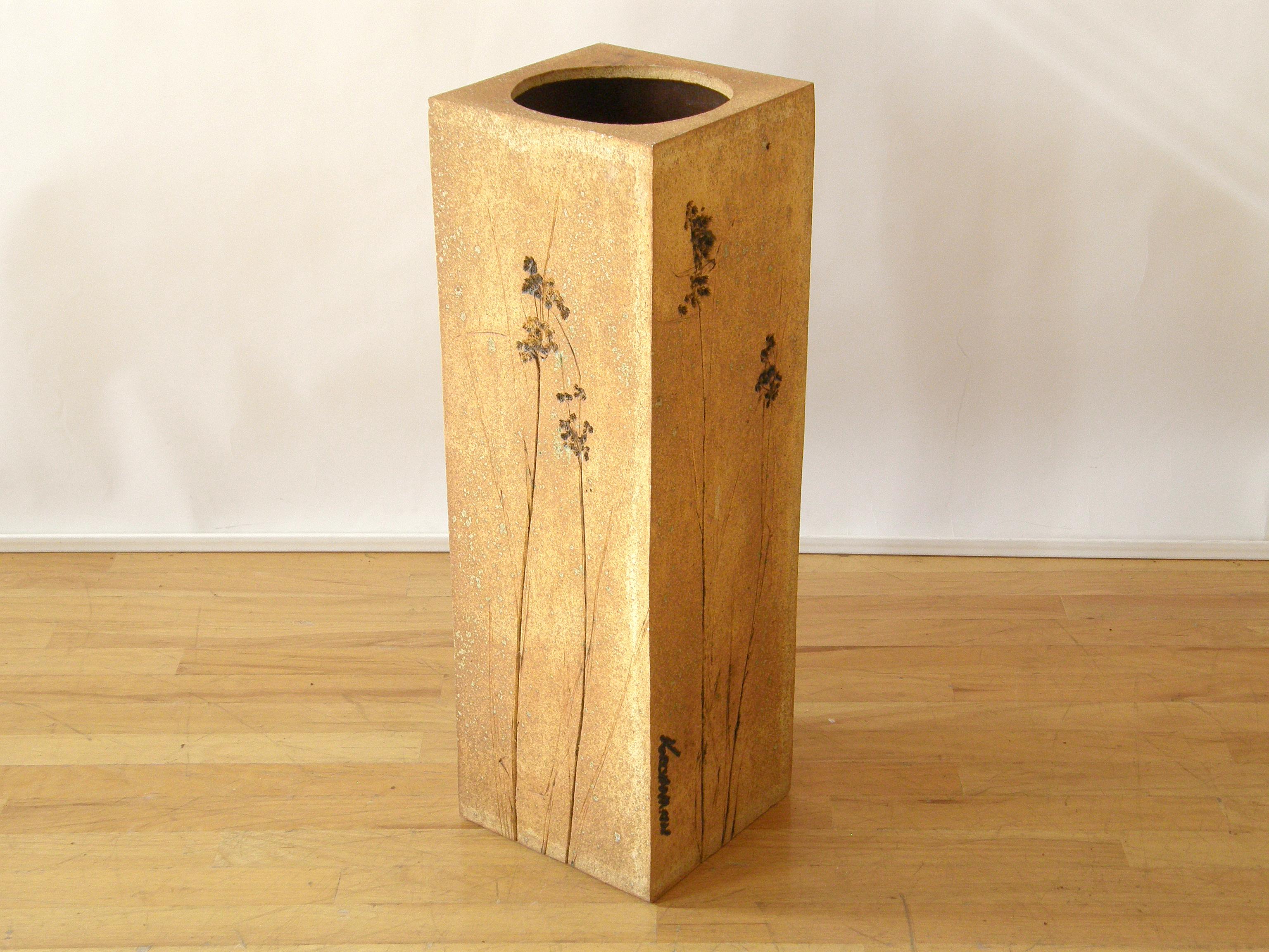This two-piece floral ceramic piece by Indiana artist Dennis Kirchmann is convertible. It can be used as a pedestal with a small amount of storage with the top on, or the top can be removed to allow access to the recessed area to hold a potted