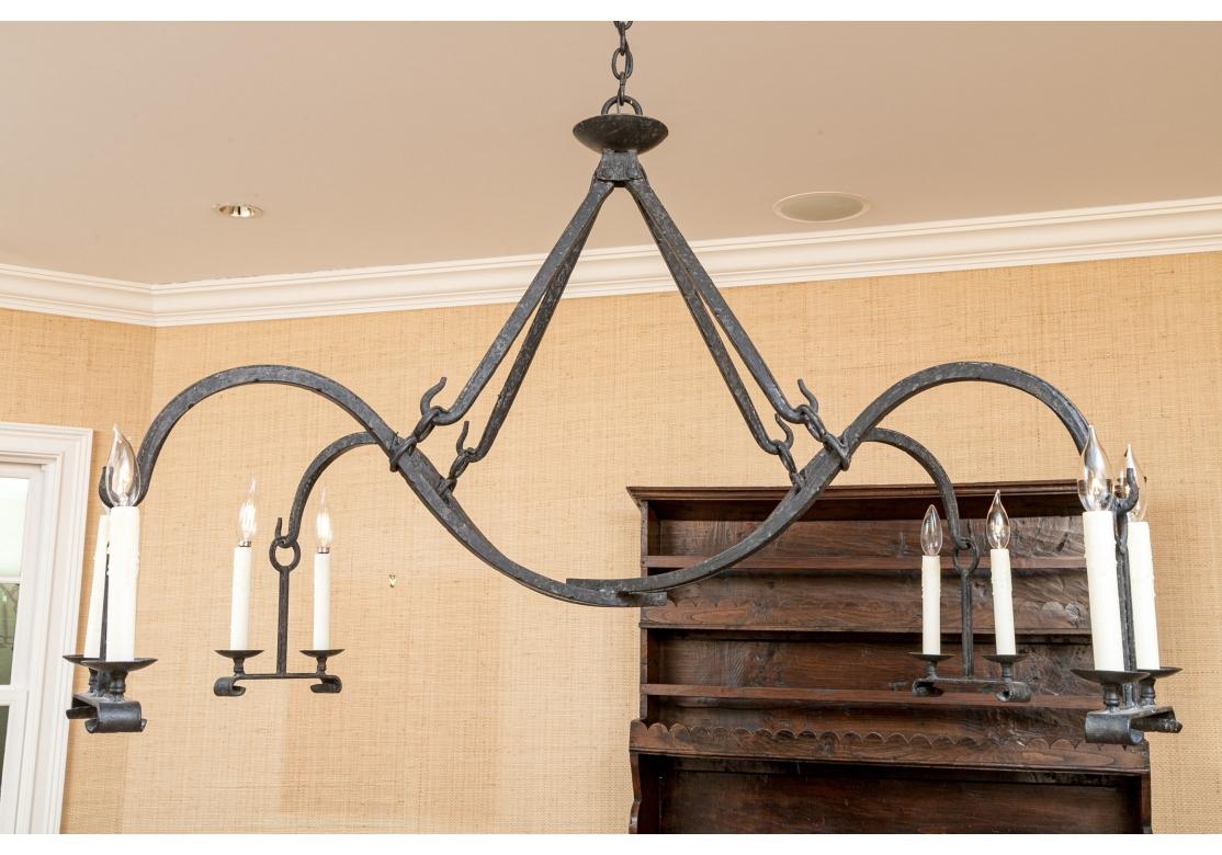 A Classic and very powerfully designed Iron Chandelier with a remarkable form. Dennis & Leen fine quality black iron chandelier comprised of two scrolling arms suspended from four fixed hooks. Each arm with two electrified wax candles mounted on