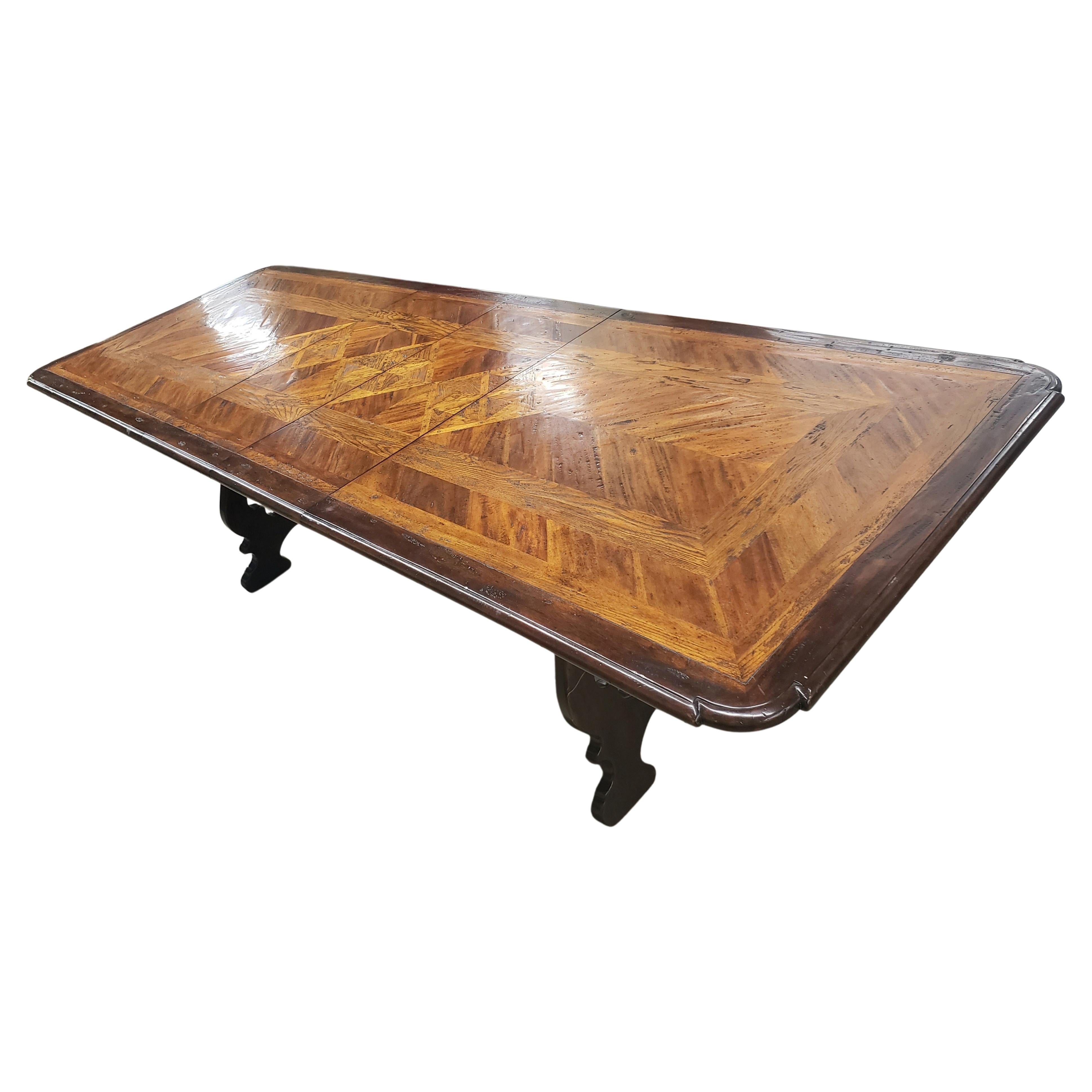 A stunning heavy parquetry dining table. Extendable with two self contained leaves of 16 inches each.
Amazing banded and book matched parquetry work of various Solid woods species, distressed by design and varnish finished. Trestle bar connected to