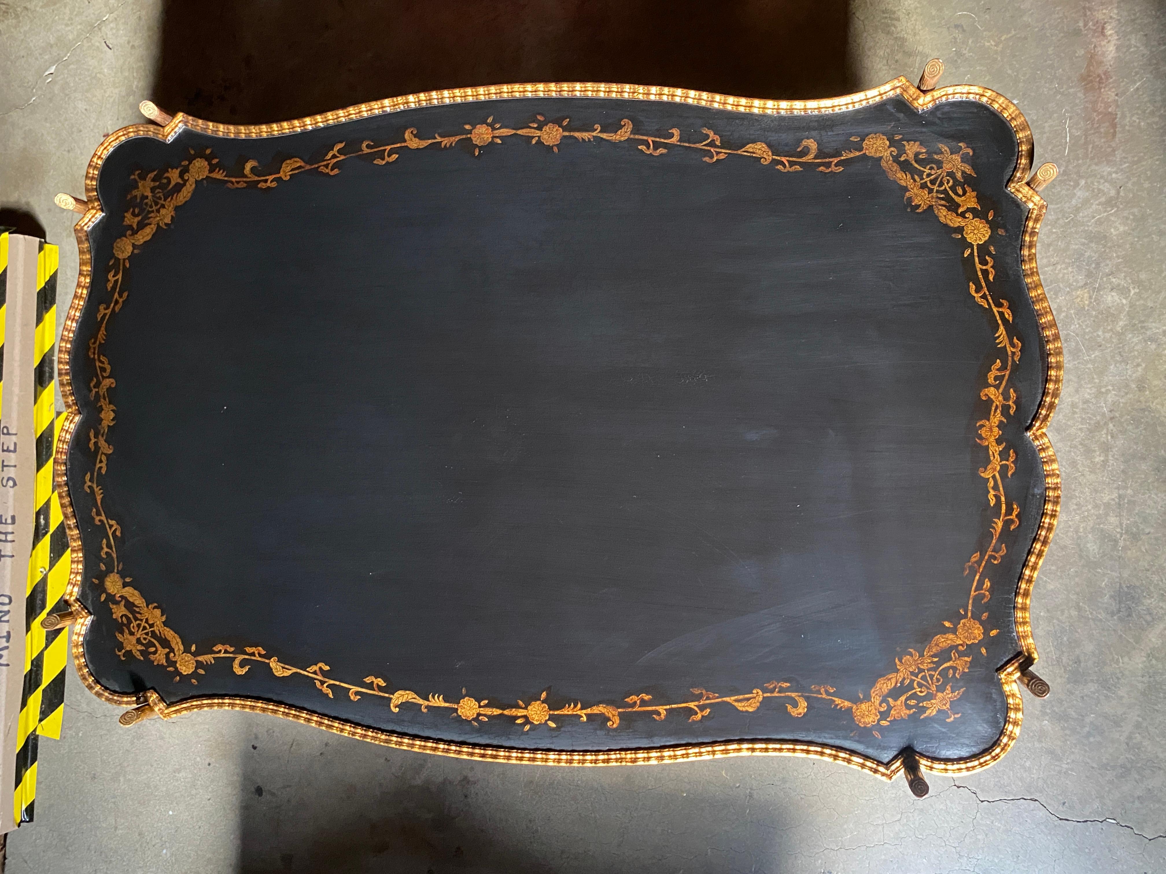 This Dennis and Leen Lacquer and Bronze Coffee Table Features a Shaped Top made of solid wood with a Crackle Finish, Distressed Gold Frame and a Hand Painted Floral Vine Border Decoration also in Distressed Gold. The Bronze Base features a