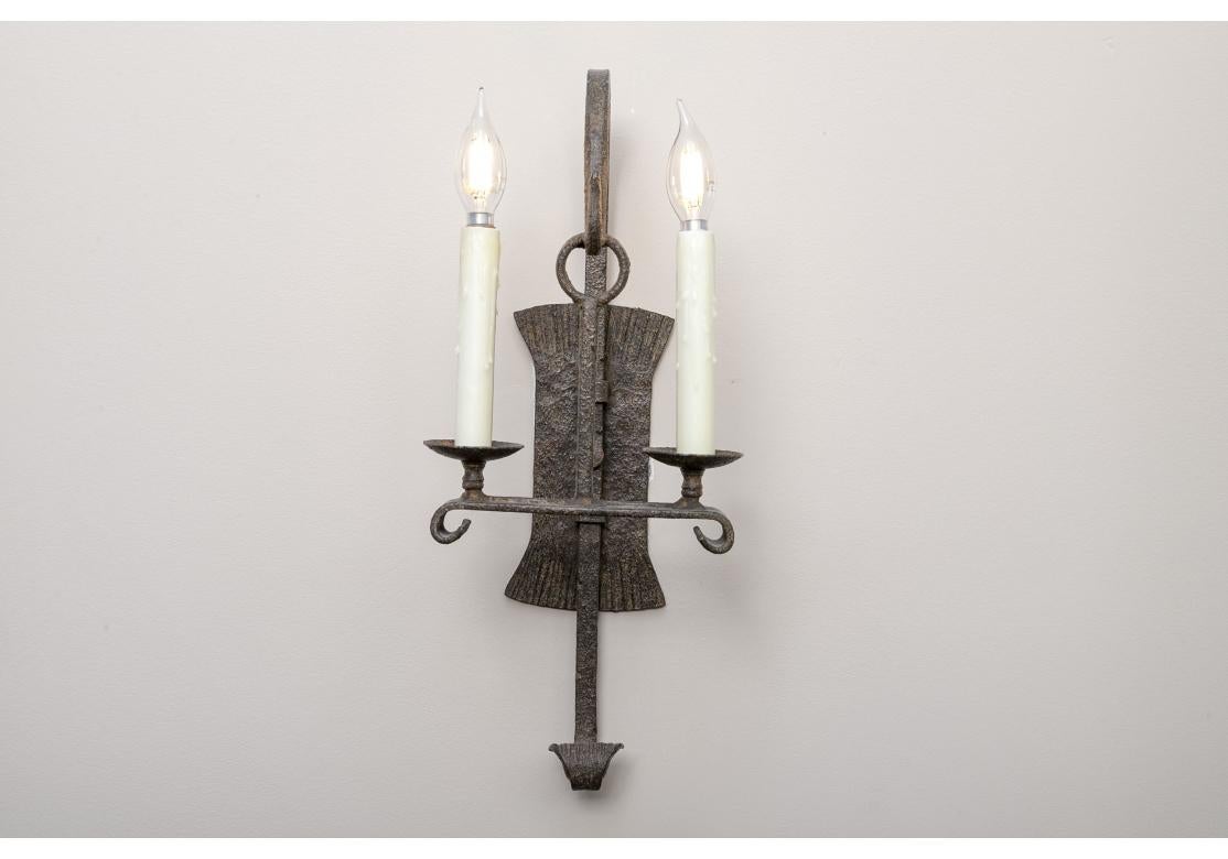 Dennis & Leen Gothic style iron wall sconces with illuminating wax candles. The sconces with two candles mounted on a scrolled altar with a ring hanger and a scrolled terminal.
Dimensions: 21 1/2