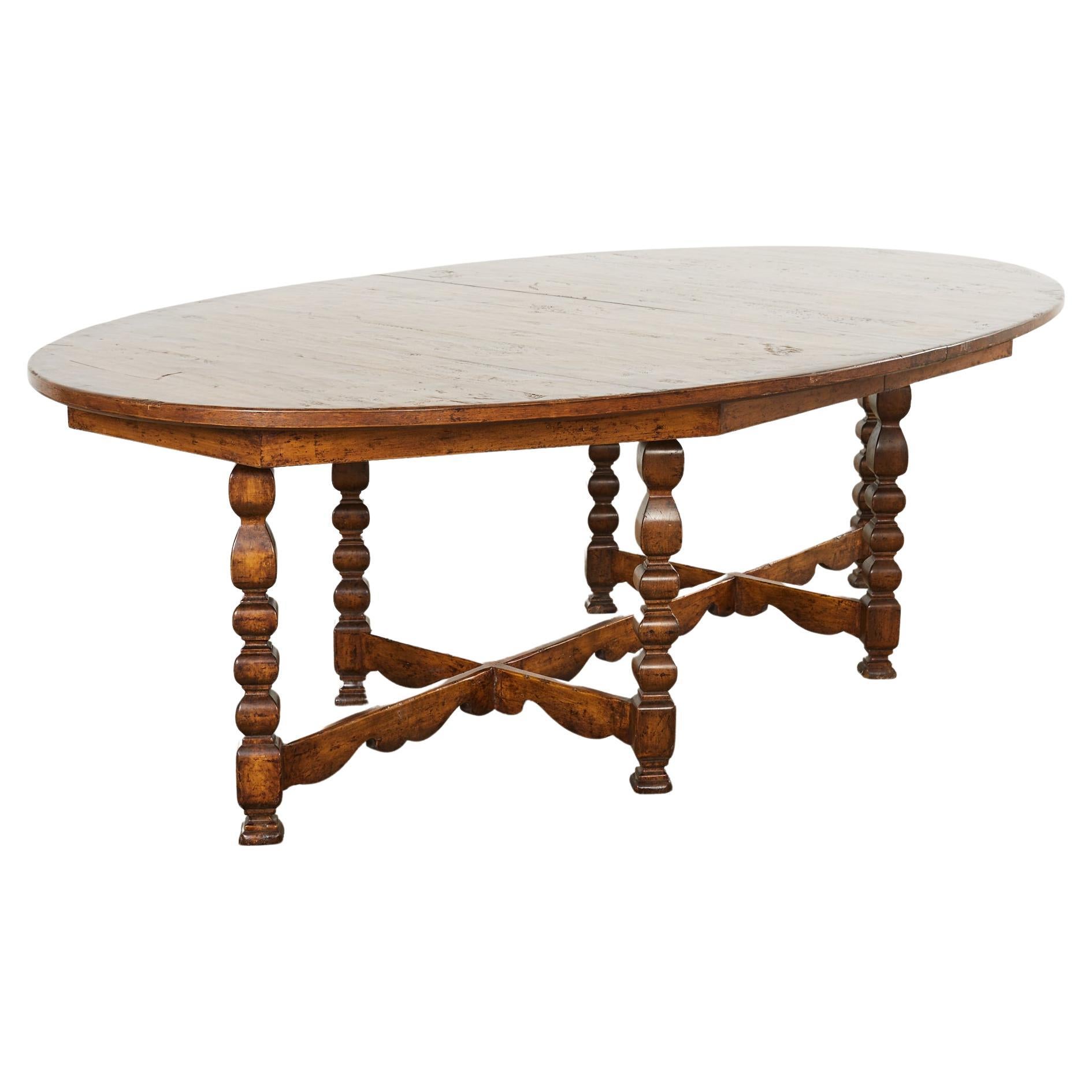 Distinctive Spanish Baroque style dining table designed by Dennis & Leen. The grand table features a large oval top supported by a six leg trestle base. The legs have a whimsical turned bobbin design with angular shapes conjoined by a long shaped