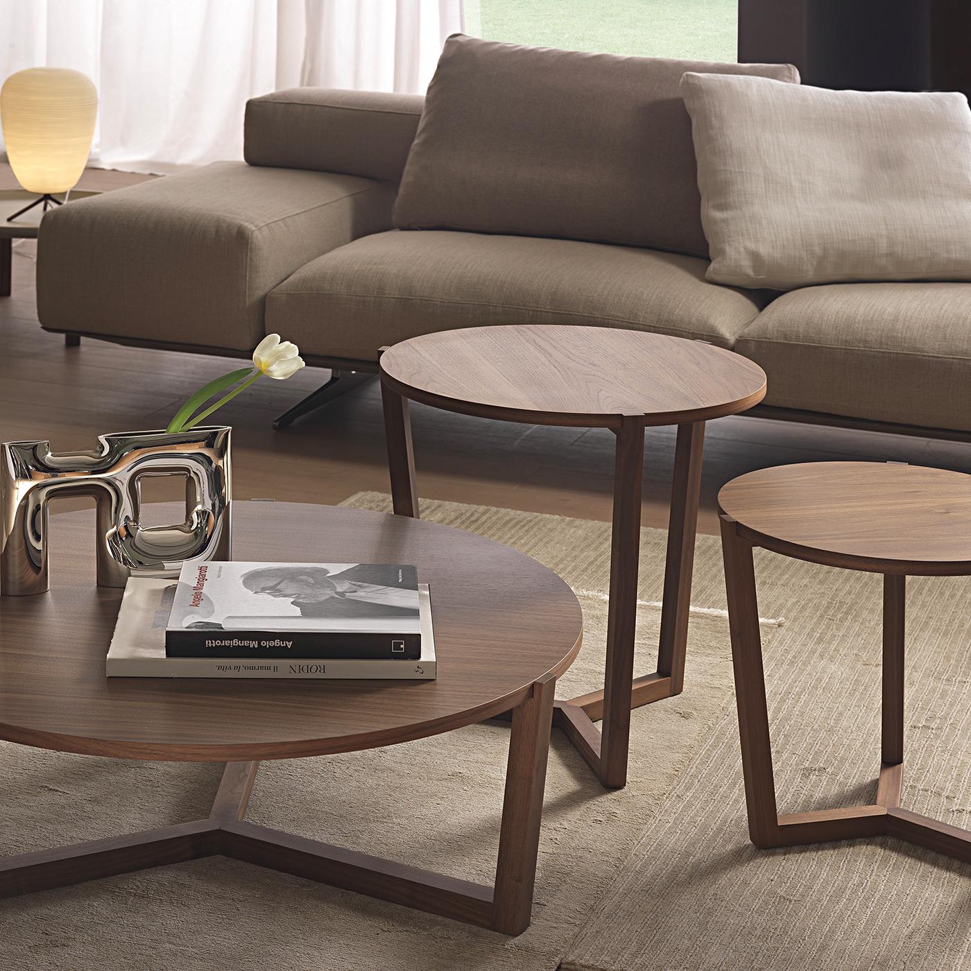 Entirely crafted of high-quality wood, this coffee table was designed to display sophistication and restraint in a minimal piece of furnishing. The rounded table top is veneered with precious Canaletto walnut wood and the three dainty legs