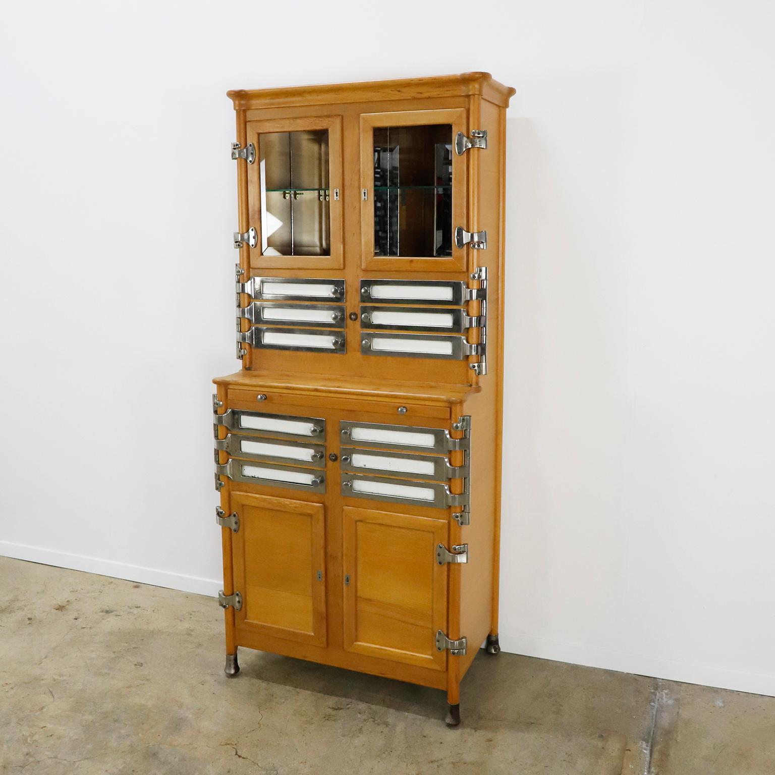 We offer this fantastic Dentist's or medical cabinet in wood and metal dating to circa 1910 by Arnold Biber, Pforzheim Germany, in excellent condition. The unique style of the sculpted top and swing-out trays were this companies signature