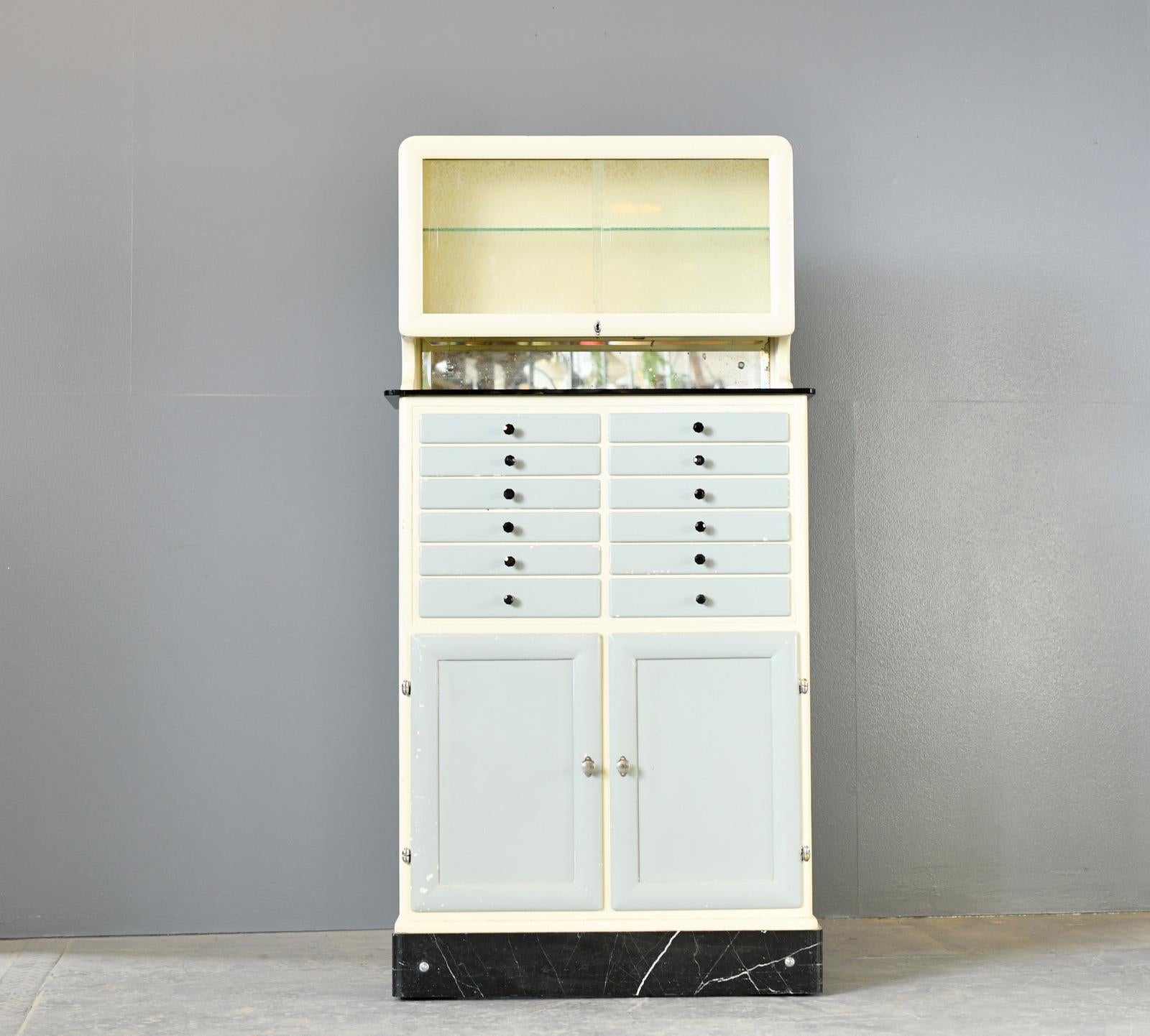 Dentists Drawer Cabinet Circa 1930s

- Pine body and drawers

- Original grey and white paint

- Black glass handles

- 12 drawers

- Black glass top with mirrored backstand

- Original patterned glass sliding doors

- German ~ 1930s

- 83cm wide x