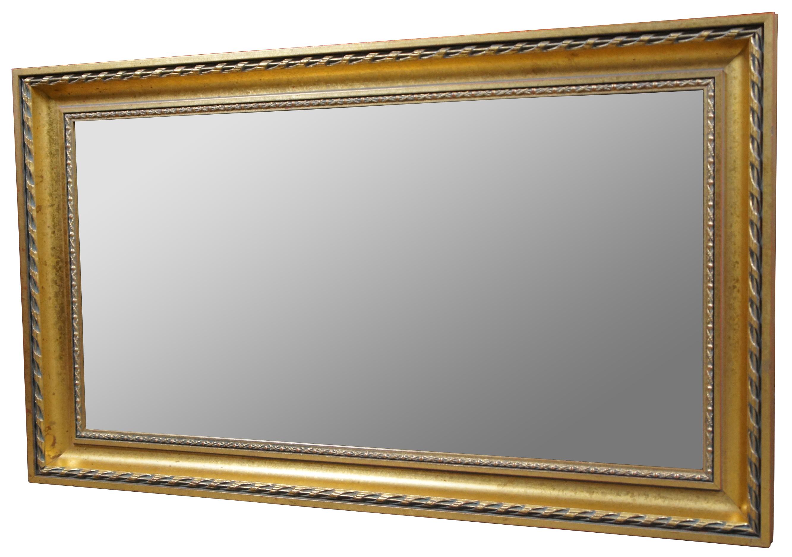 Hollywood Regency or Louis XV style gilt wood wall mirror by the H.A. DeNunzio Company. Features a rectangular frame with ribbon trim outside of a french inspired X patterned trim and beveled glass mirror.

Measures: 20.25” x 1.75” x 34” / Mirror