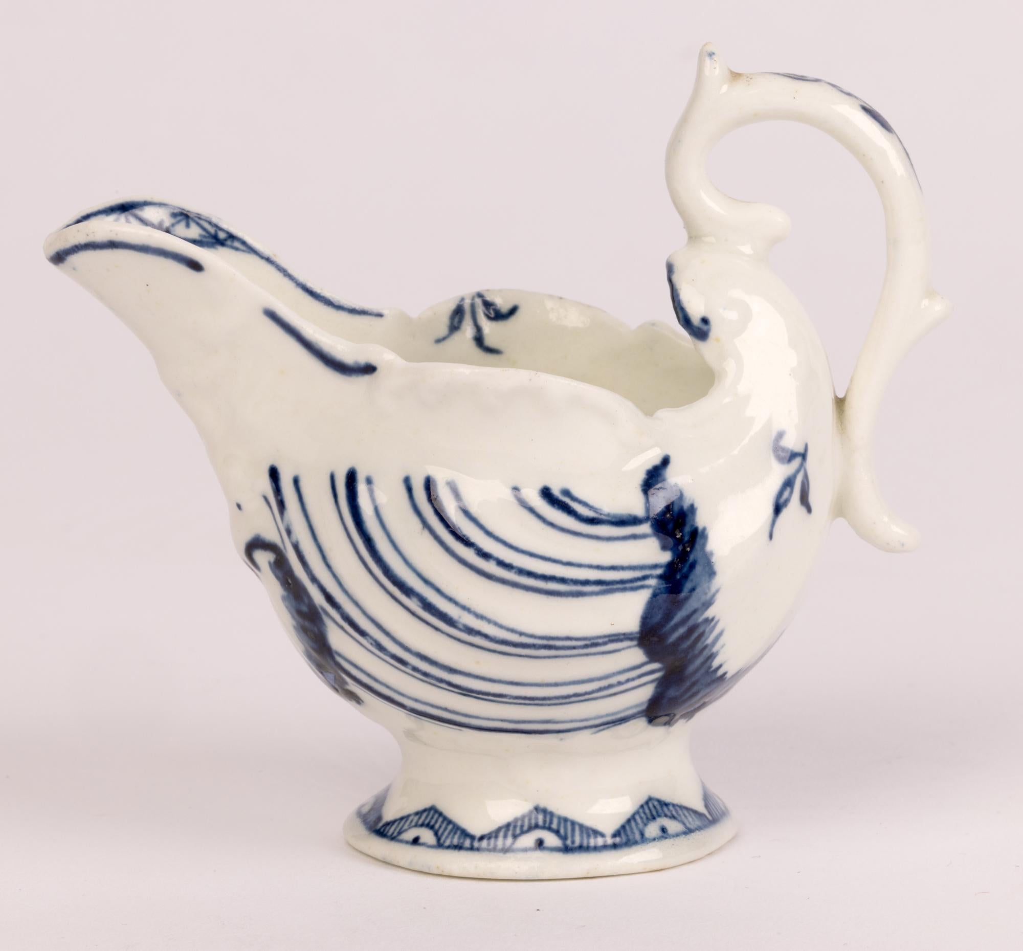 A fine antique Georgian English porcelain Dolphin and Shell molded butter boat by Derby and dating from around 1770. The small jug shaped vessel stands raised on a round pedestal base with a molded scroll work body and with a raised large pouring