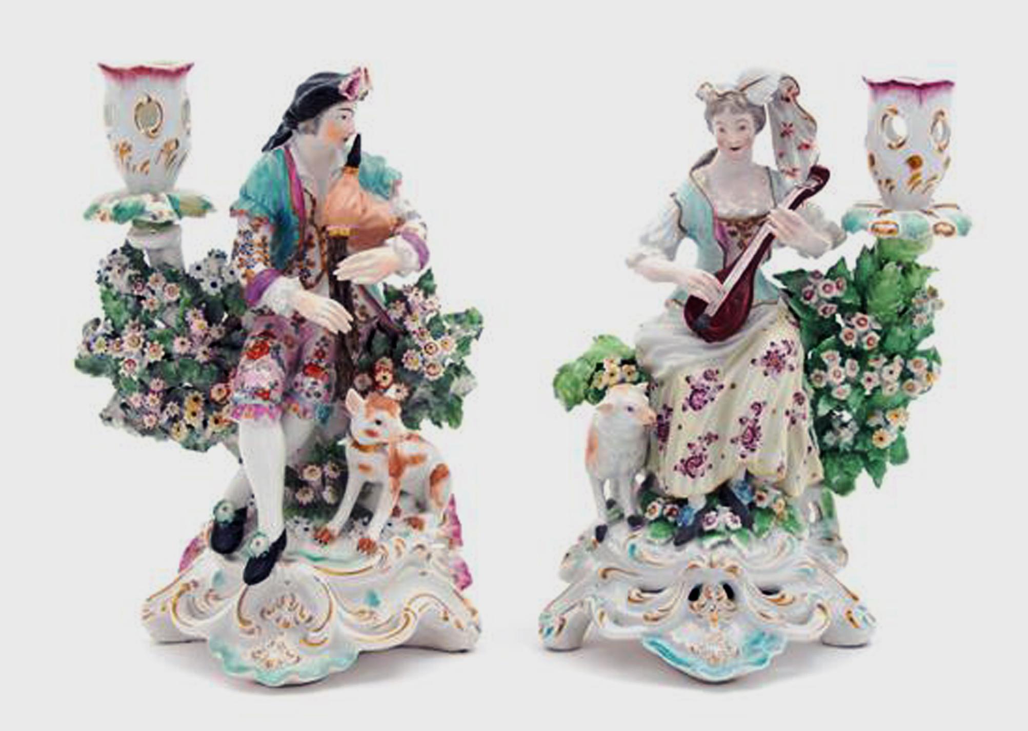 Derby Porcelain candlesticks with figures of musicians, 
circa 1760-1765

The pair of Derby Porcelain figures of musicians are on an openwork scroll base, the man is playing the bagpipes with a dog at his feet and the woman plays a lute with a lamb