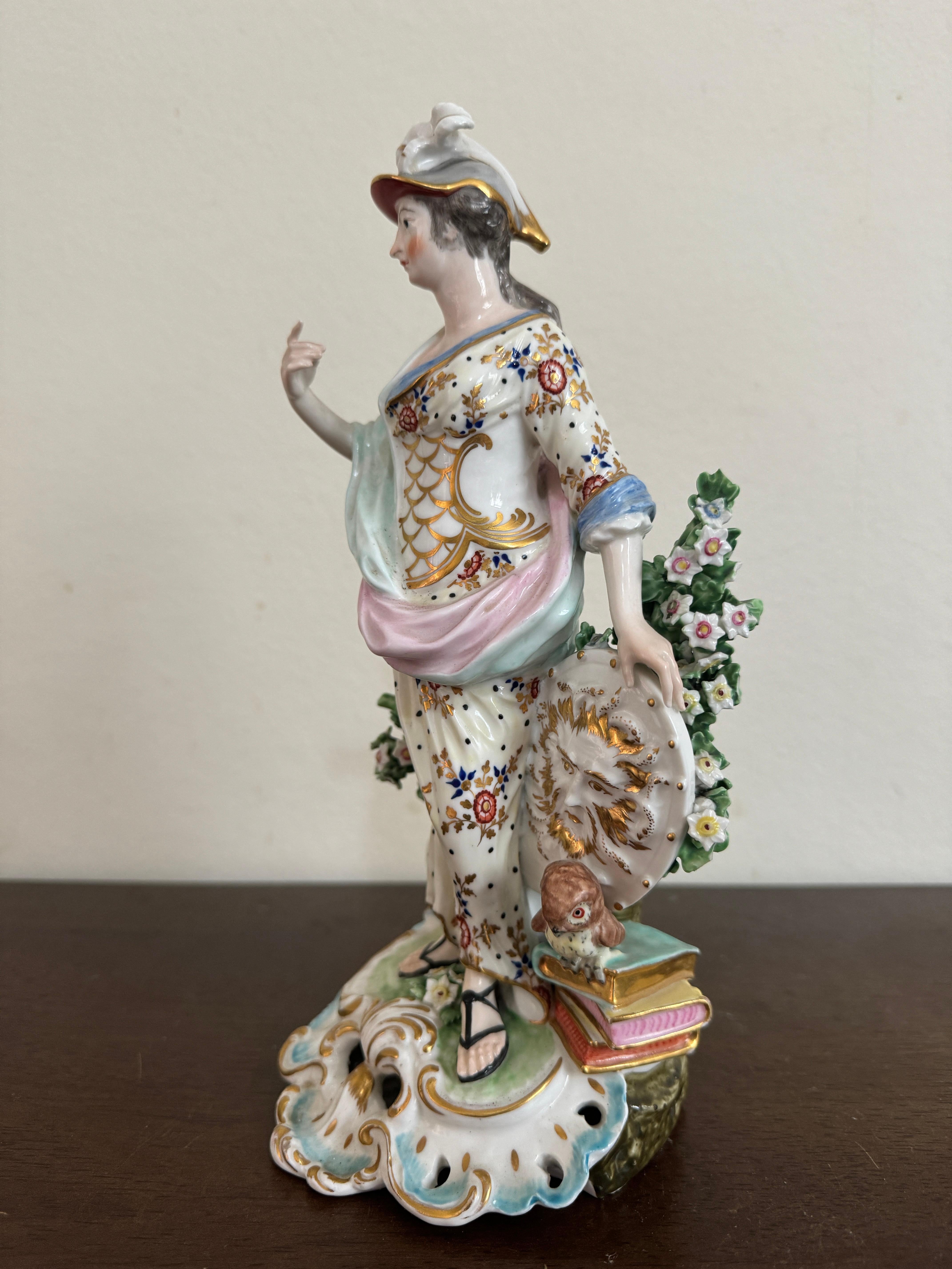 Figura di Minerva in porcellana Derby, 1780 circa, in piedi con una veste di colore giallo pallido, su una base a volute traforate blu e dorate, altezza 26 cm