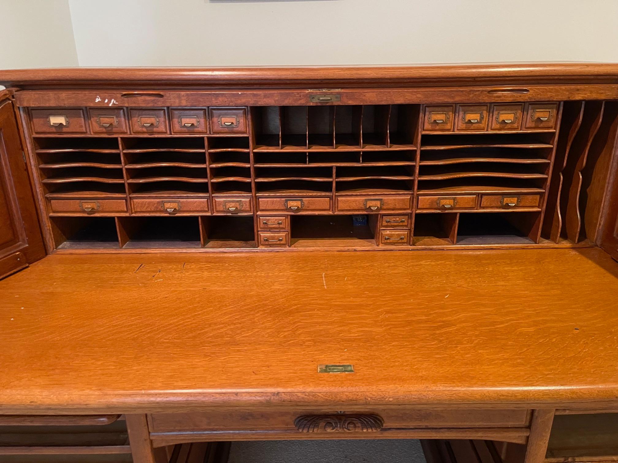 Escritorio Enrollable de Roble Panelado de la Escuela Derby con Interior Completo, Circa 1900.  El escritorio tiene una estructura de paneles de roble aserrado en cuarto con apertura en S para un interior completo sobre una base con torres de