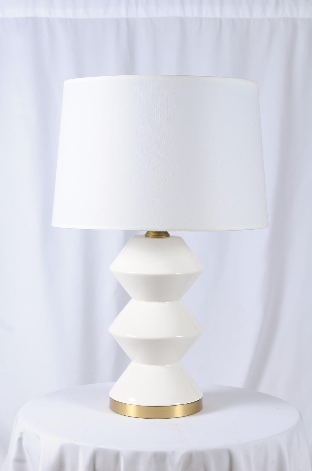 Derby table lamp. White ceramic with a gloss finish and a solid unlacquered hand-rubbed antique brass base with brass socket with upgraded switch turn key. Made in the USA by Fox Mill Lighting & Supply, and a 60 watt bulb recommended.
Measures: 28
