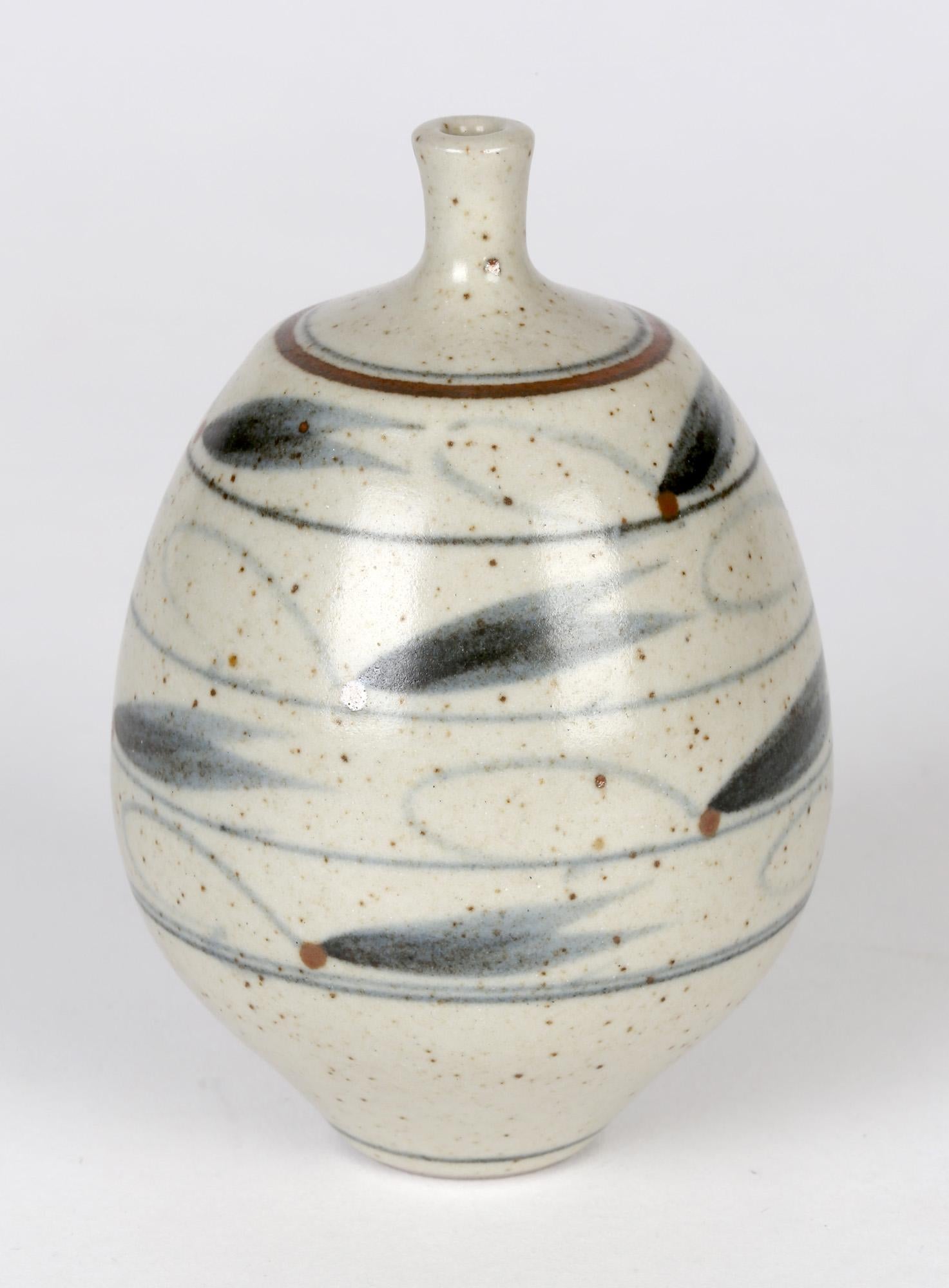 A good and finely made studio pottery stoneware bottle vase of small size decorated with a repeat brush pattern of stylized insect like designs by Derek Clarkson (1928-2013). The vase of rounded bulbous shape stands on a narrow flat rounded foot