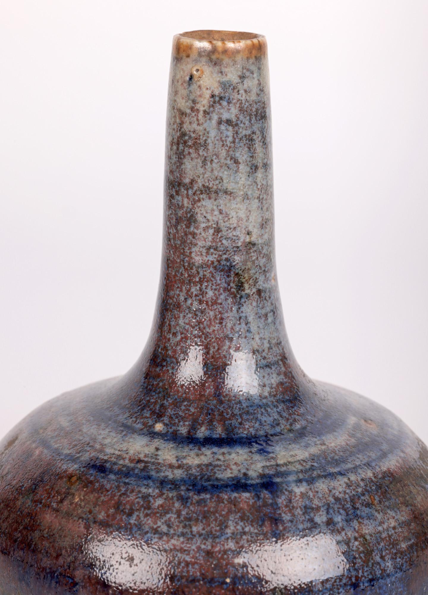 A finely potted bottle shaped bud vase decorated in blue glazes by renowned Sussex based potted Derek Davis (British, 1926-1908) and dating from around 1960. The heavily made hand-thrown stoneware vase stands on a narrow round unglazed foot rim with