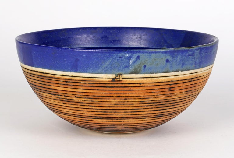 A fine large Blackfriars Pottery studio bowl with a horizontal linear pattern and decorated in blue glazes by Derek Smith (British, 1931-2019) and dating from the 20th century. The heavily hand thrown round shaped bowl stands on a narrow unglazed