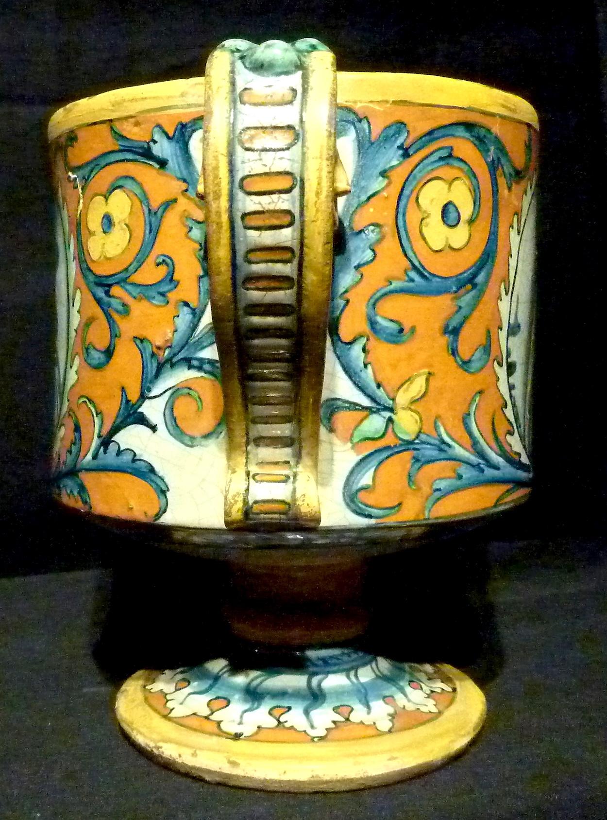 Cup, Deruta, first half of the 16th century, in majolica decorated in ocher tones of blue, green and yellow, with floral scrolls that frame virile busts in classic clothes on the reverse and on the recto, two volute handles, circular foot, height 18