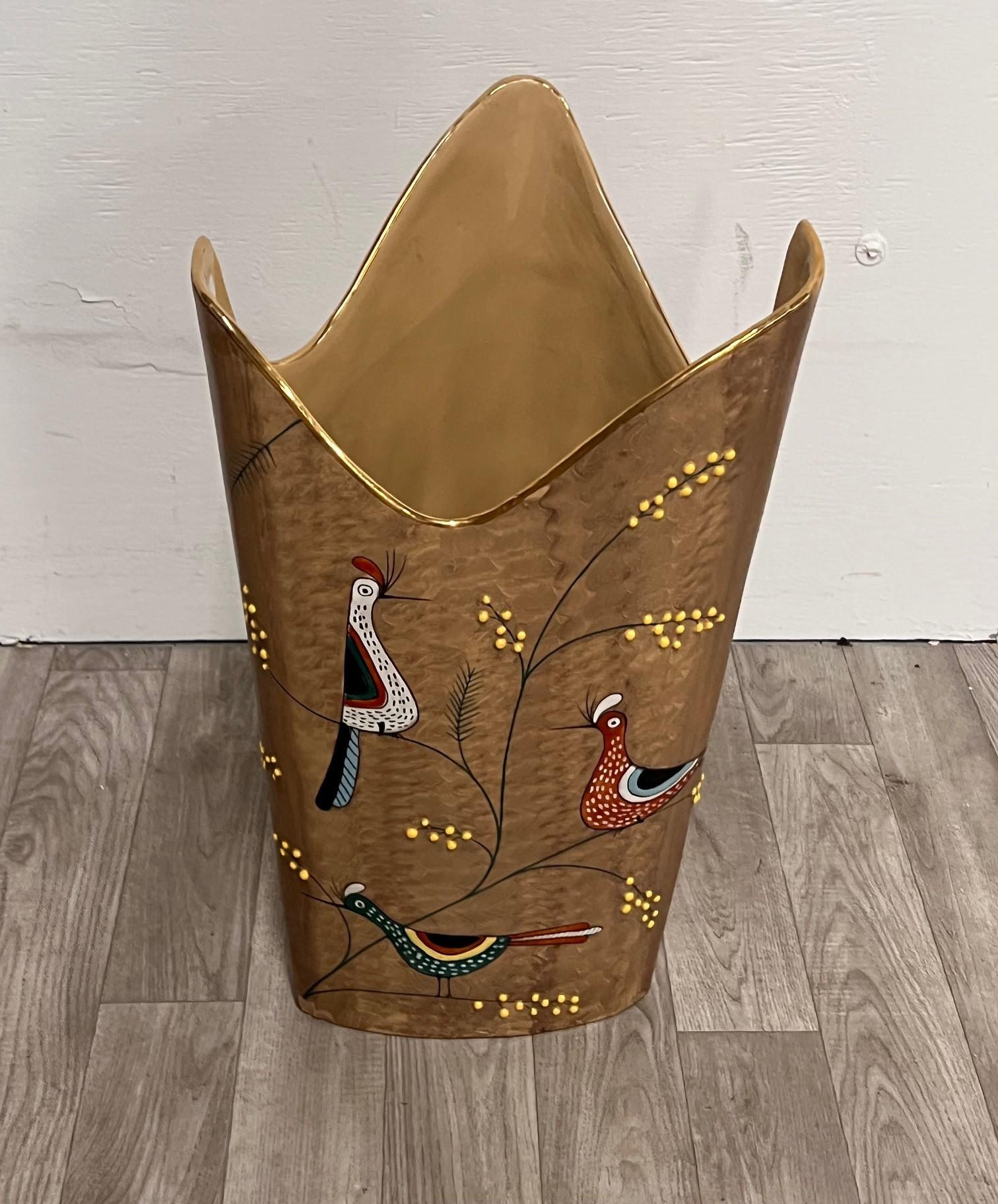DERUTA
Made in Italy, ca. 1950.
Umbrella stand in brown glazed ceramic decorated with mimosa branches in relief, polychrome birds, triangular body with shaped mouth decorated in pure gold. Production mark and label of origin.