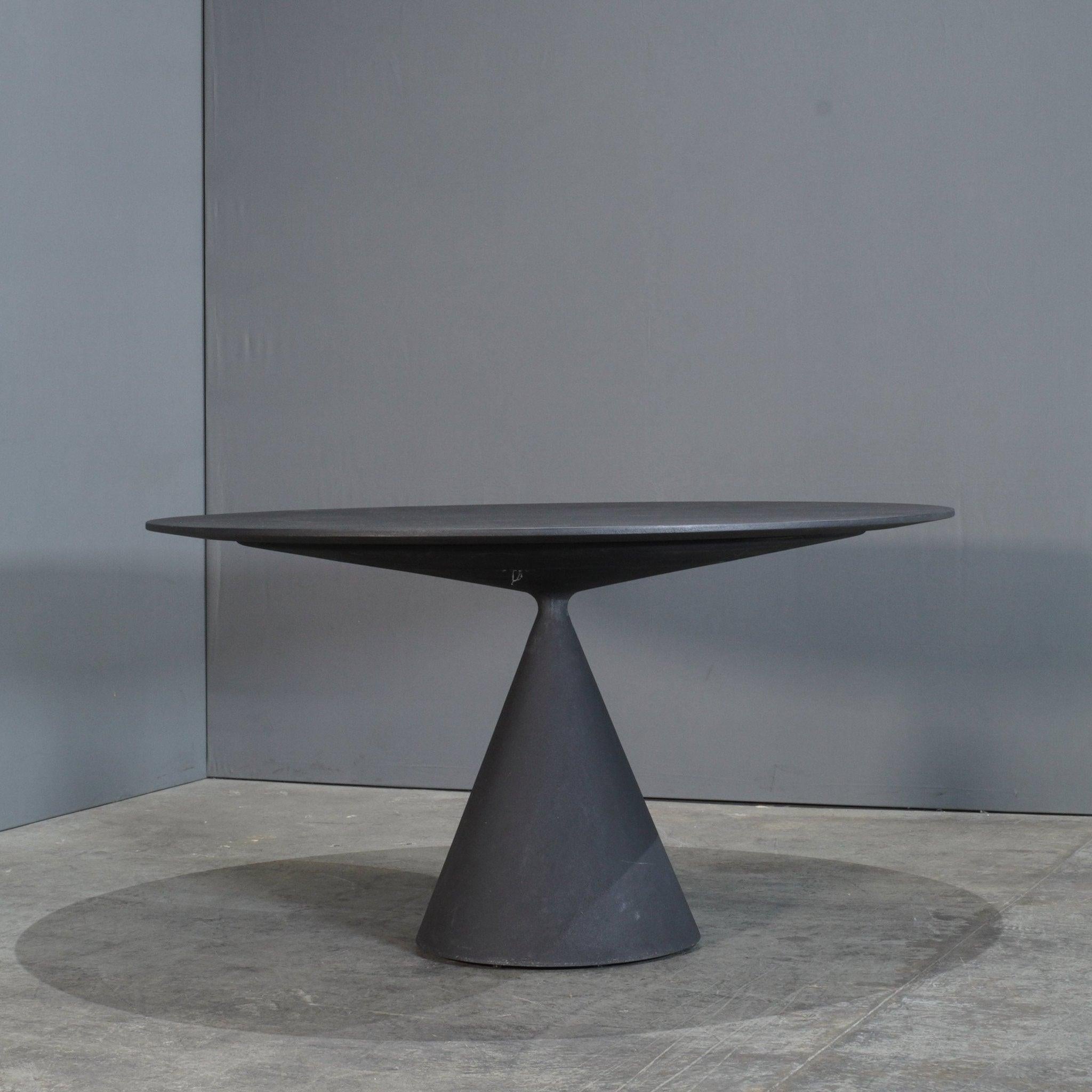 The Desalto Clay Dining Table by Marc Krusin is a stunning balance of form and function, featuring a sculptural design that effortlessly commands attention. Its unique silhouette comprises two intersecting geometric forms: a round tabletop and a