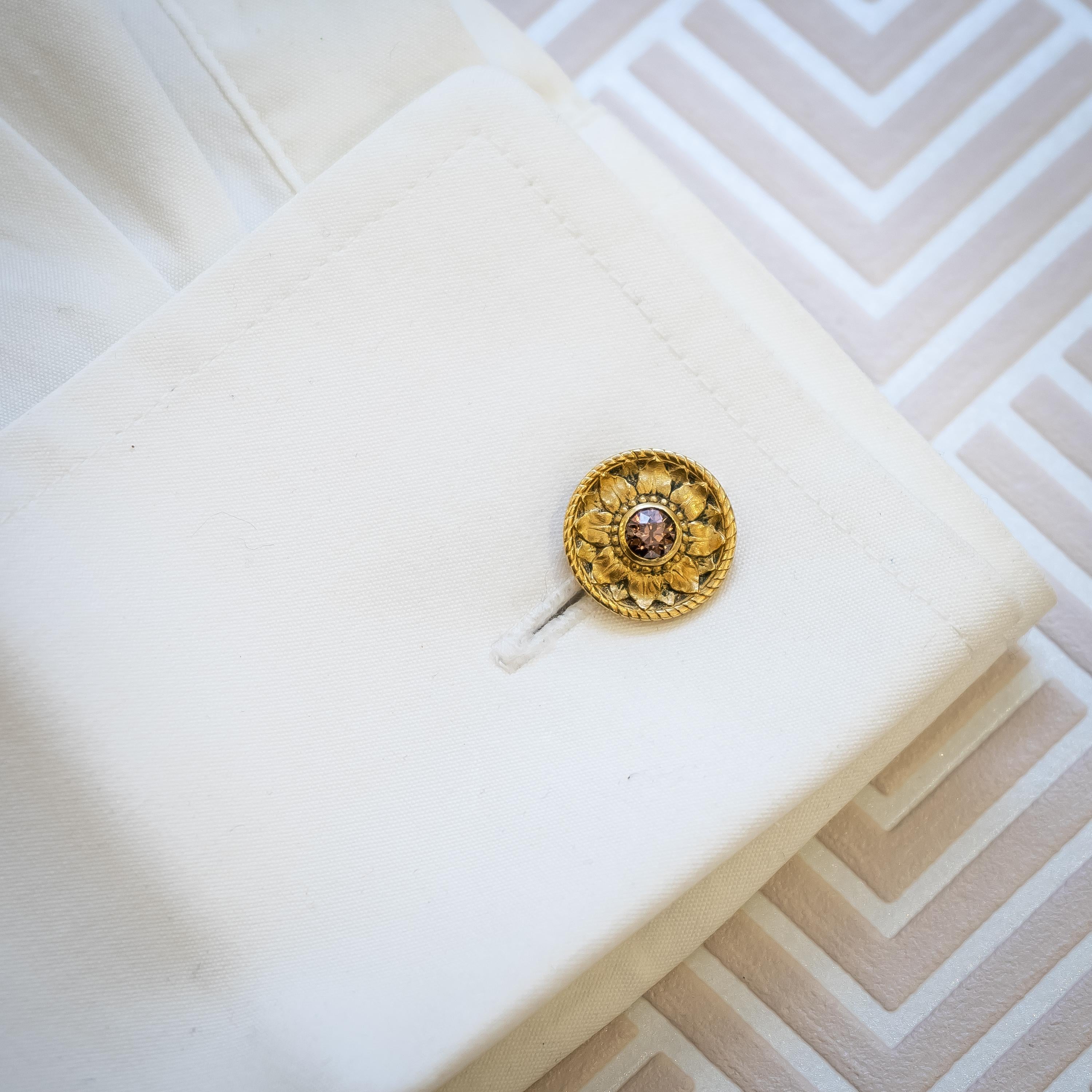 A pair of French, Art Nouveau, champagne brown diamond and yellow gold floral cufflinks, for Maison G. Desbazeille, with old-cut pink toned dark champagne brown diamonds, in rub over settings, in the centre of engraved sunflower like flowers, with a