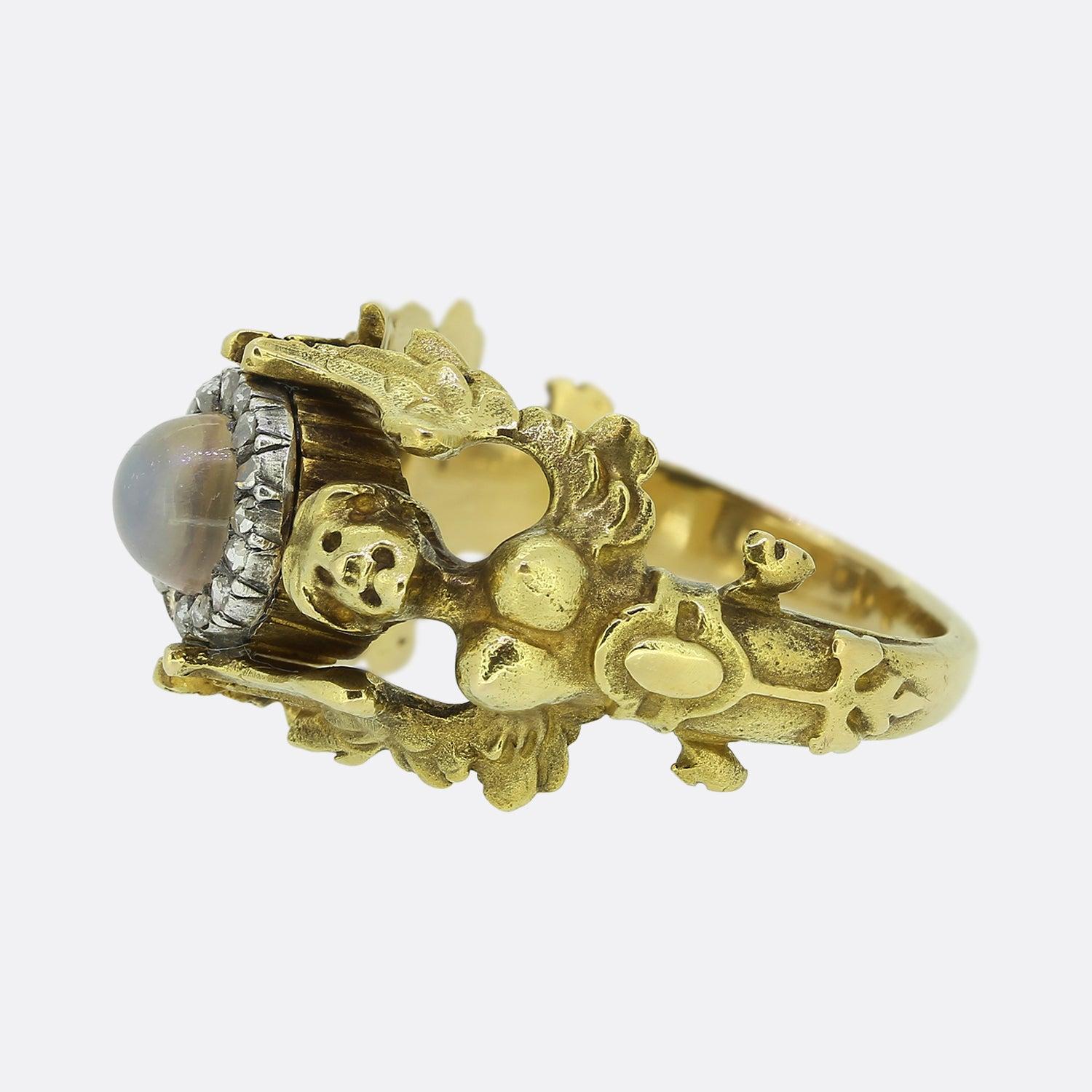 This is a truly special ring dating back to the late 19th century. The ring features two perfectly detailed angels that pose back to back and hold up a central moonstone and diamond cluster. This ring is perfect for collectors and would make a