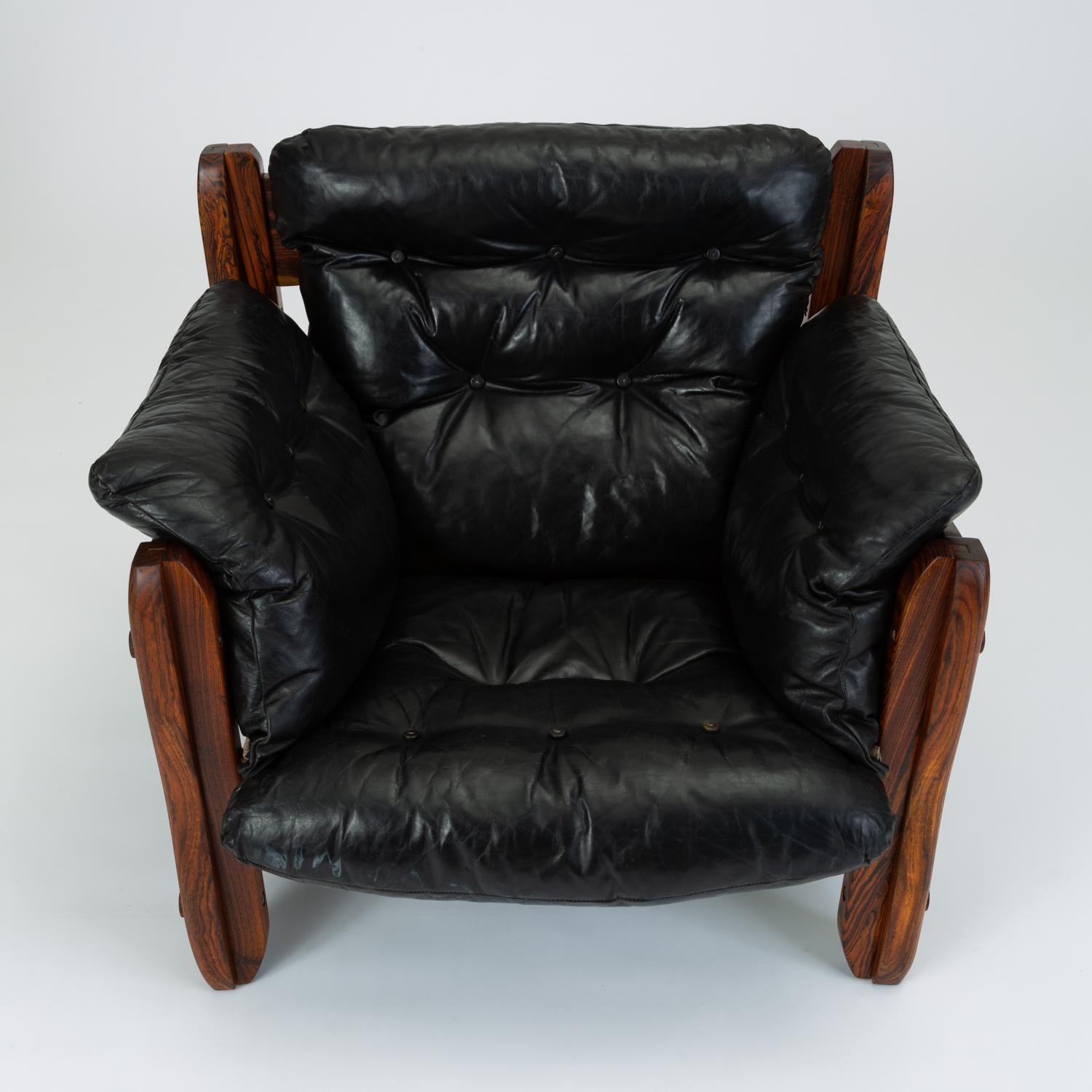 A deep, wide lounge chair from Don Shoemaker’s “Descanso” line produced in highly figured cueramo wood and black leather. The blocky construction and broad planes of the frame showcase the almost marbled appearance of the woodgrain, while the wavy