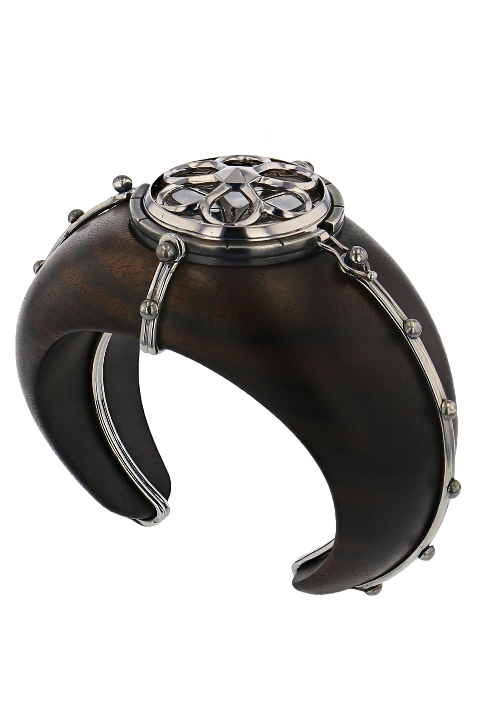 Macassar ebony cuff embellished with a white gold cage, featuring a pivoting disk adorned with a rosette design in grey gold on distressed silver, revealing a pierced dome studded with diamonds and blue topazes, accented with lapis lazuli and
