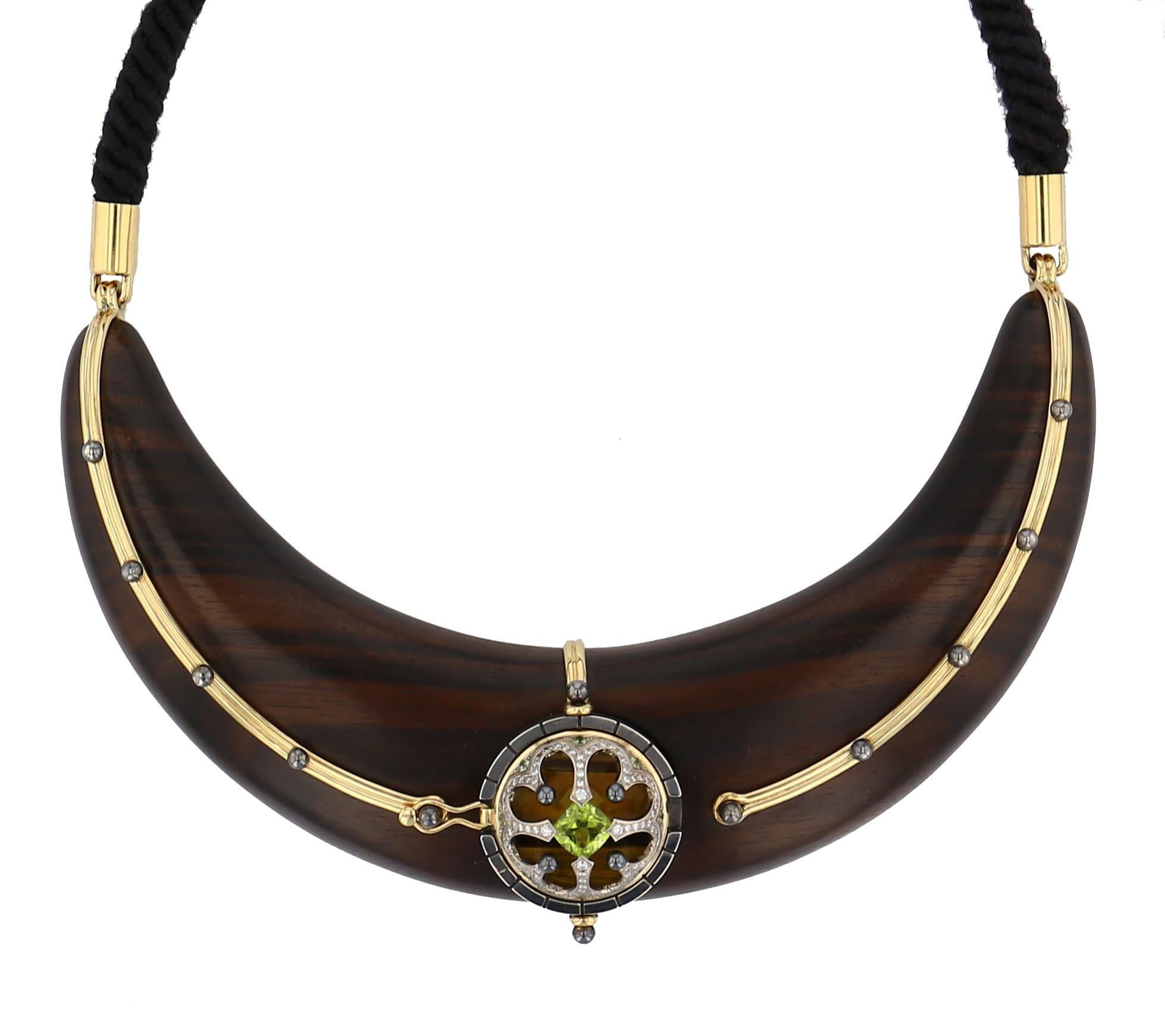 Large torc sculpted from Macassar ebony, accentuated with studded yellow gold threads, mounted on black cotton braid. At the centre of the necklace, a pivoting sphere reveals a yellow gold rosette on patinated silver, when closed, which opens to