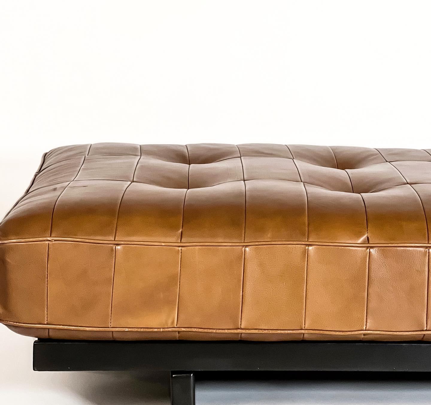 Classic modernist patchwork leather daybed by De Sede. 8” thick cushion rests upon a slatted constructivist lacquered wood base. Top comfort and timeless design; a dreamy place to rest and relax in any space. This early 1970s example has been