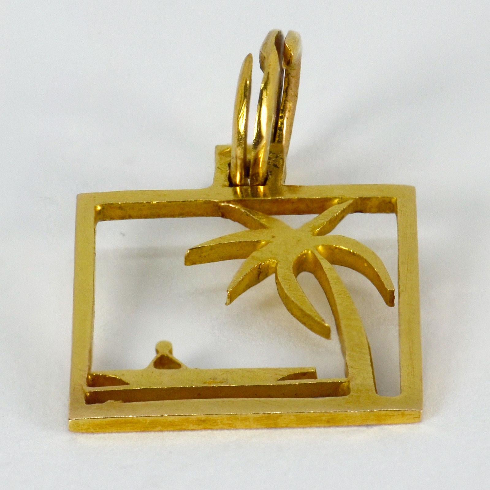 An 18 karat (18K)  yellow gold square charm pendant depicting a desert island palm tree and boat. Stamped with the owl mark for French import and 18 karat gold.

Dimensions: 1.8 x 1.5 x 0.1 cm (not including jump ring)
Weight: 1.70 grams
