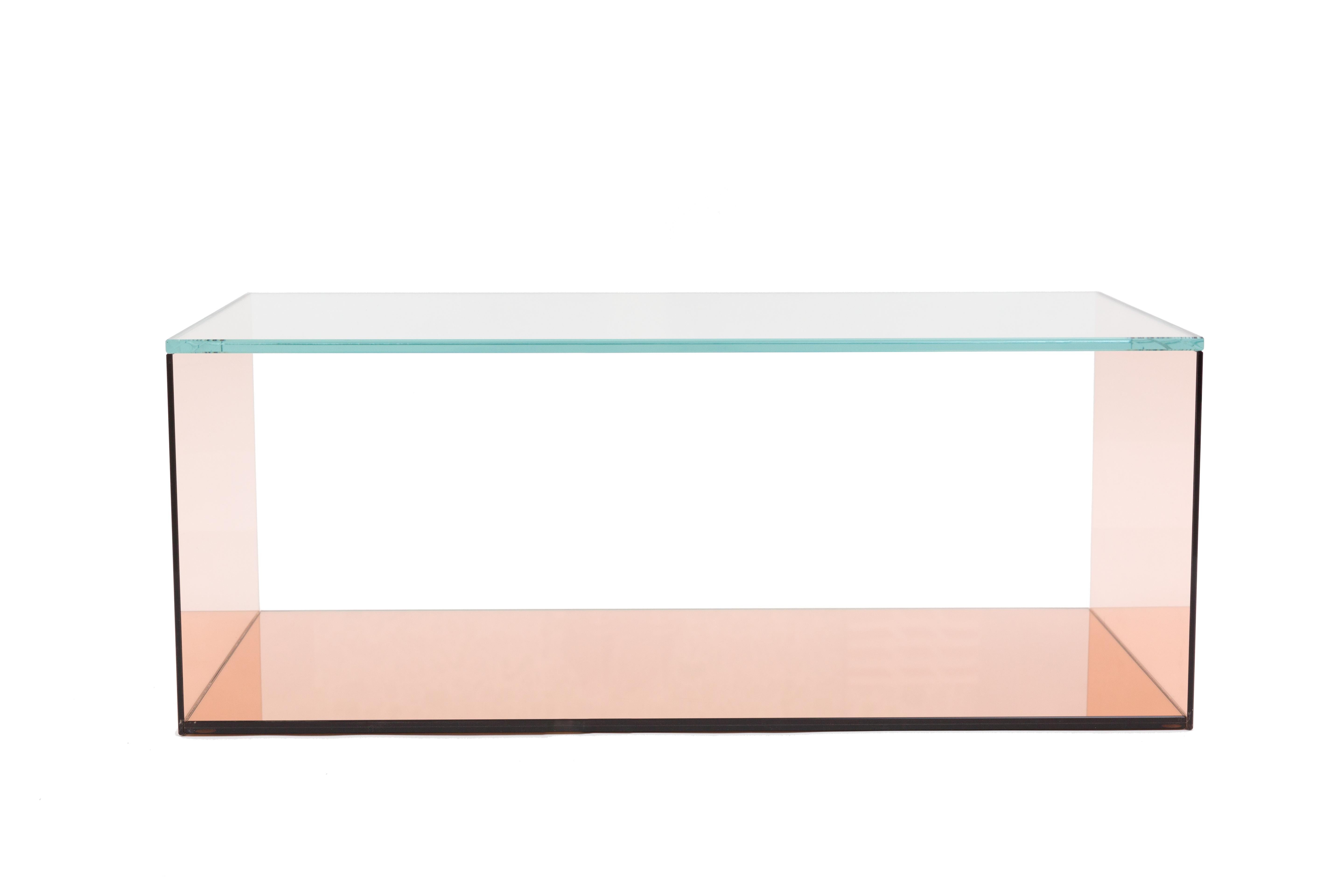 Coffee table of peach glass and mirror with an intriguing union of transparency and luminosity. Peach glass planes sides cap a clear glass top and back panel. The open front allows for decorative storage. The interior base is a peach mirror surface,
