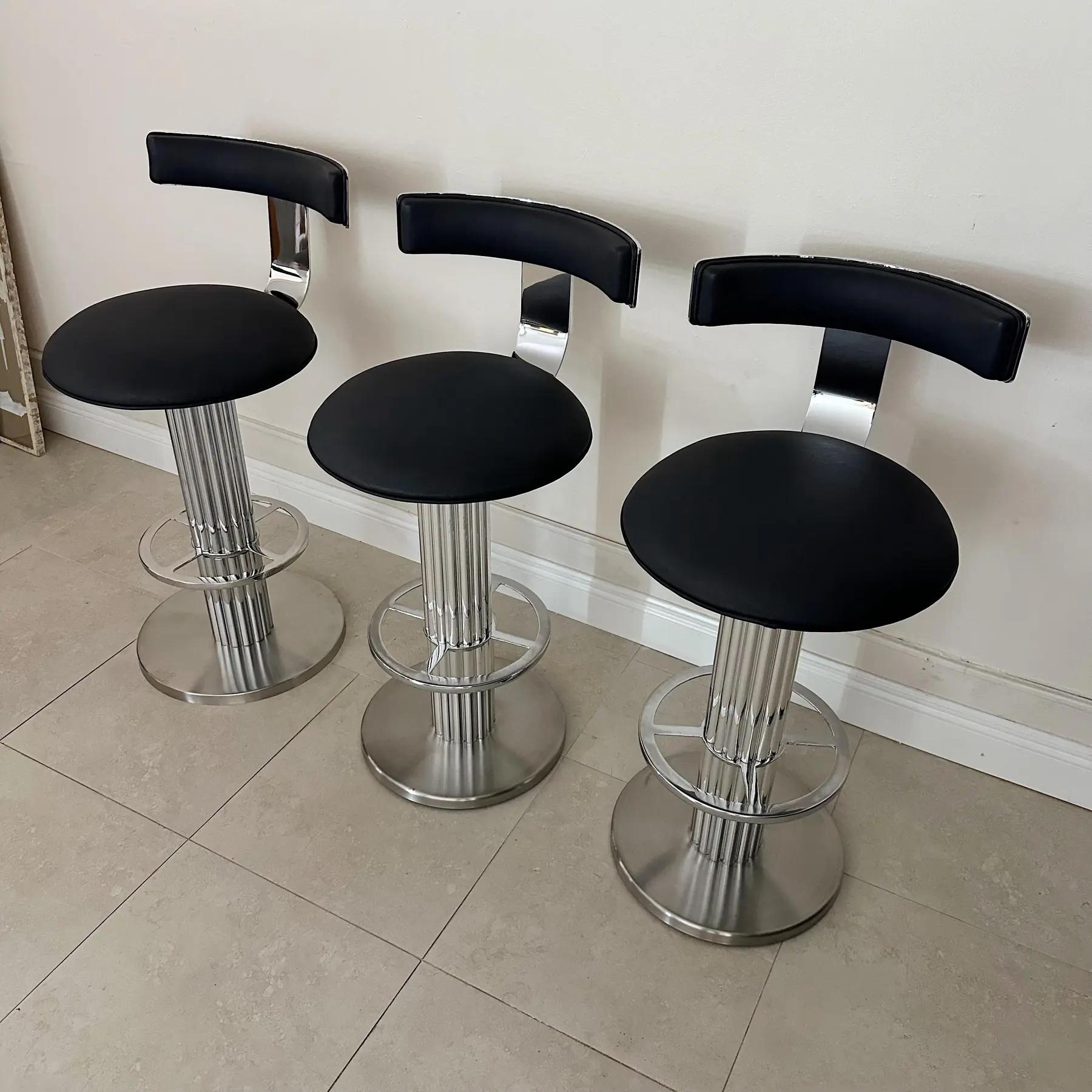 Set of 3 Design for Leisure swivel barstools in chrome with footrest. Professionally polished and reupholstered in black leather. From NY in the 1980s. Seat Height: 30.5