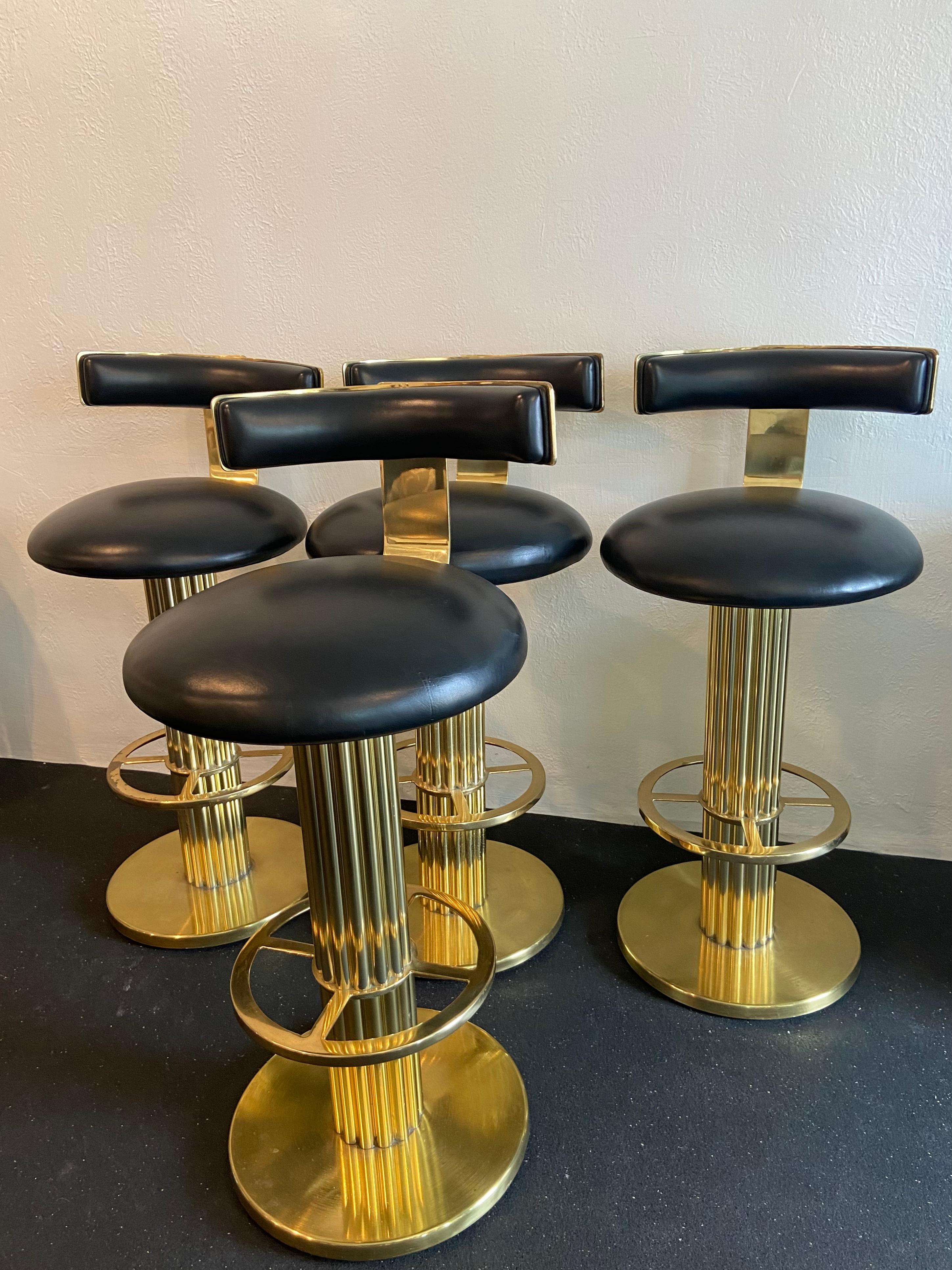 Set of 4 brass swivel barstools by Design For Leisure. The stools retain the original leather upholstery, which does show some signs of wear however remains intact with no rips or tears. The clear coat has worn in some areas which has led to some