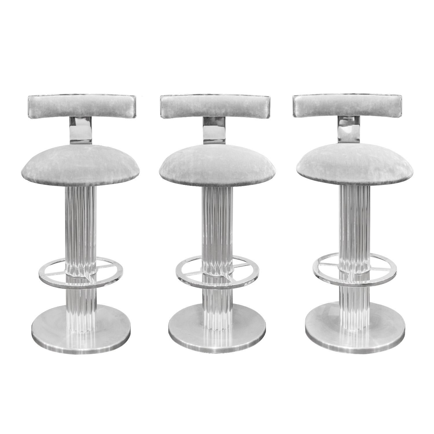 Set of 3 finely crafted bar stools in stainless steel with fluted bases and floating back rest by Design for Leisure, American 1970's. Metal has been professionally cleaned and polished. Seats have been newly reupholstered in gray velvet by Lobel