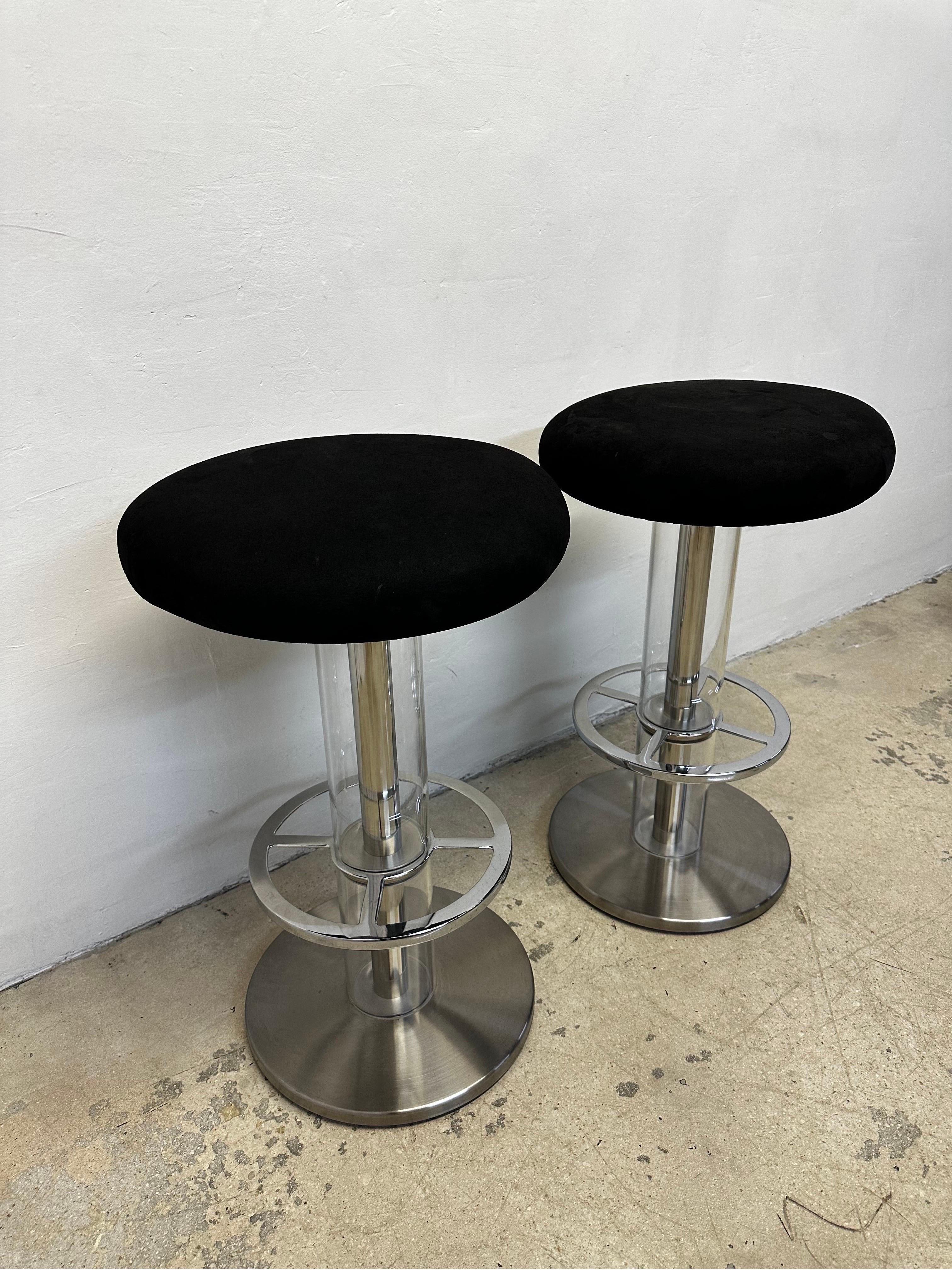 Pair of Design For Leisure bar stools with black ultra suede swivel seats supported by a steel frame base with clear acrylic tubes.  

Fabric shows stretching and wear.  New upholstery recommended.