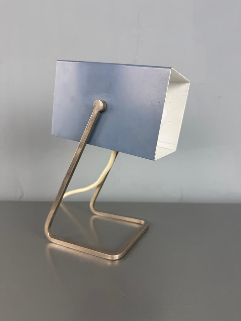 Brilliant piece of design! This lamp is as iconic as small. Beautiful architectural sixties desk- or table lamp by Kaiser Leuchten, Germany. The model number is 45097. The color is really amazing, it's very stylish ice blue. 

When the lamp is