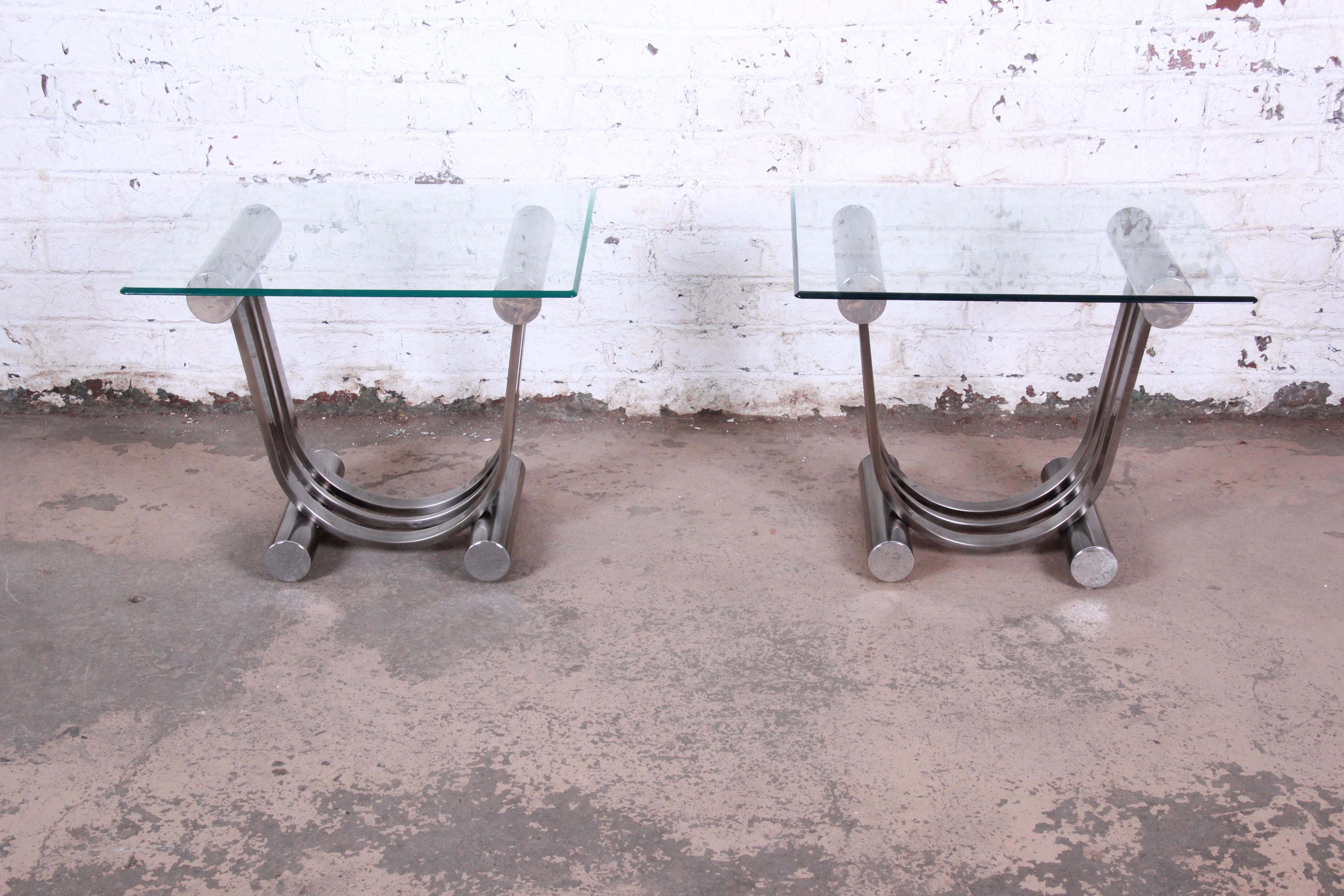A unique pair of Art Deco style chrome and glass side tables by Design Institute America. The tables feature harp-shaped chrome bases and thick glass tops. The original DIA labels are present. The tables are in excellent original vintage condition.