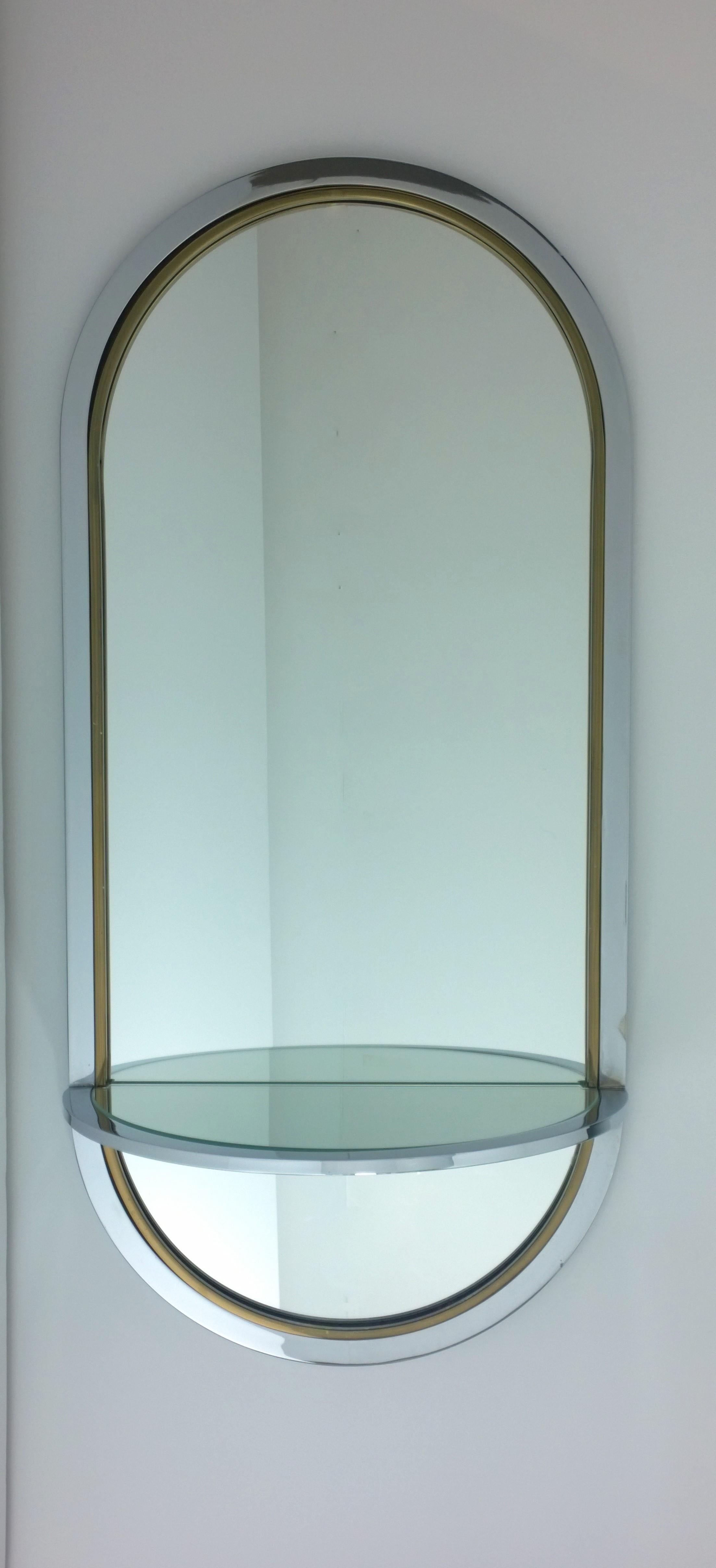 Offered is a Mid-Century Modern chrome with brass accents frame wall mirror with attached console ledge or shelf by Design Institute America. Blending metal and glass is the hallmark of Design Institute of America. Although, I believe intended as a