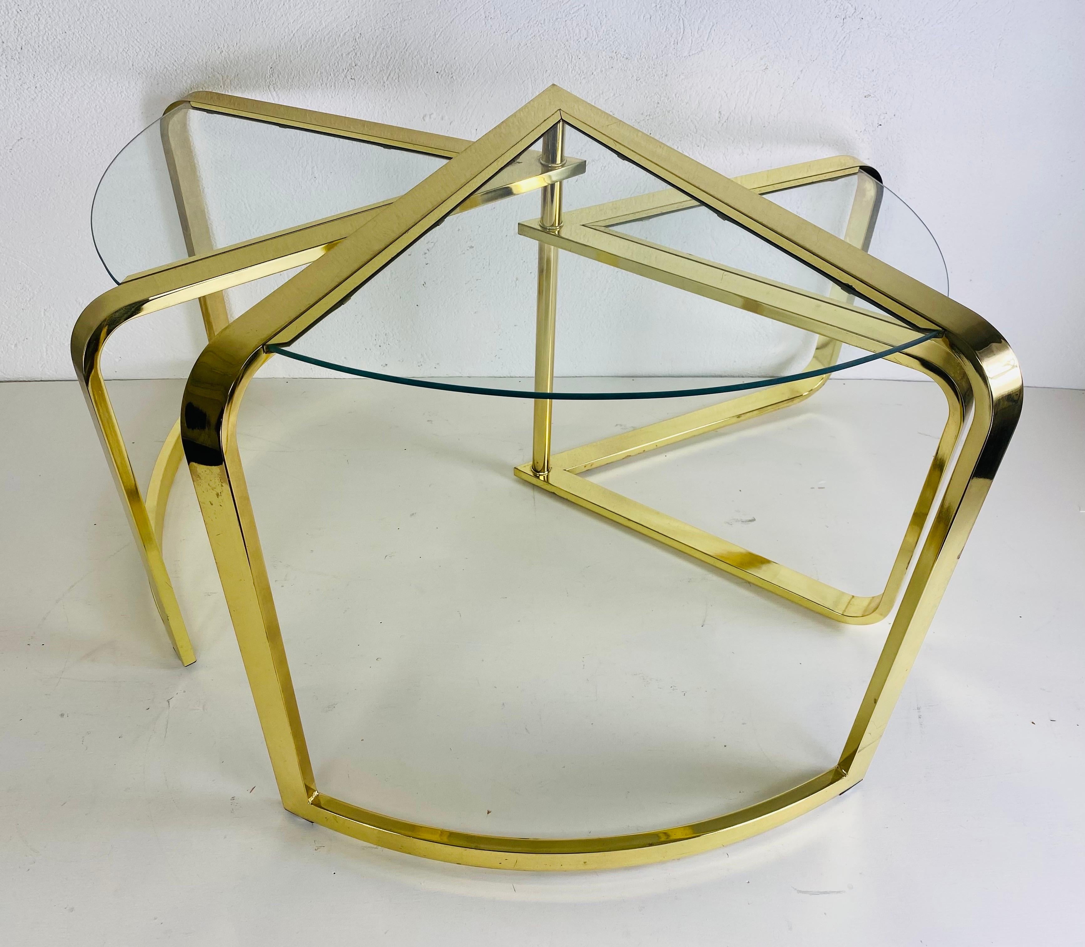 This is a mid century modernist brass nesting table by design Institute of America. This unique nesting table fans out from a single pole on the back end of the table. The table has three sections that graduate large to small. This unique mid