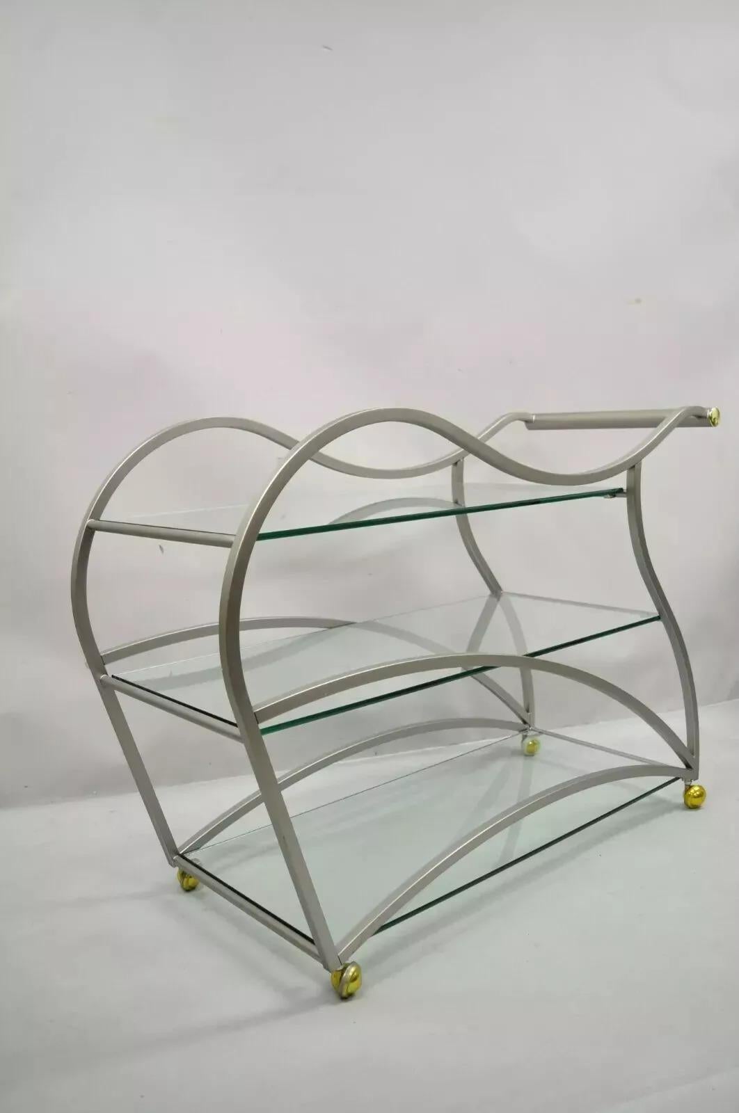 Rick Lee para Design Institute America Carrito de bar escultórico de metal cepillado. Acabado en níquel cepillado, ruedas giratorias, detalles de latón, 3 estantes de cristal, artesanía estadounidense de calidad y forma escultural. Finales del siglo