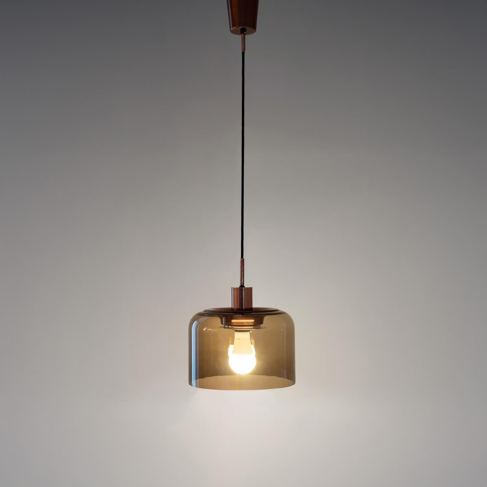 Elegant Italian pendant light manufactured in Italy in the 1970s, featuring a smoked glass shade and polished bronzed fittings. 

The minimalist design emphasizes the contrast between the warm  polished tones of bronzed iron parts and the subtle