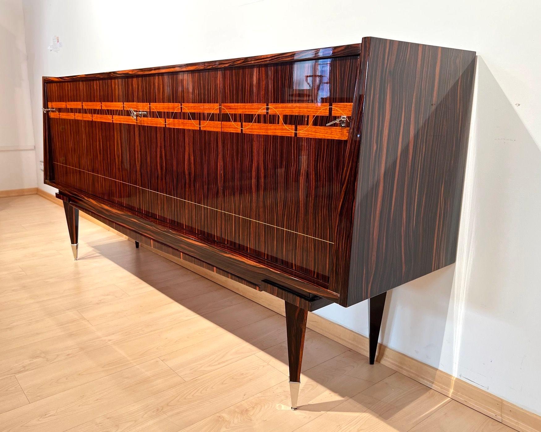 Large modernist Design Sideboard in Macassar Ebony by NF Ameublement from France circa 1960.
* Elegant modern design.
* Gorgeous Macassar Ebony veneer. Inlaid in maple on the front of the doors.
* Lacquered and high-gloss pished.
* Standing on