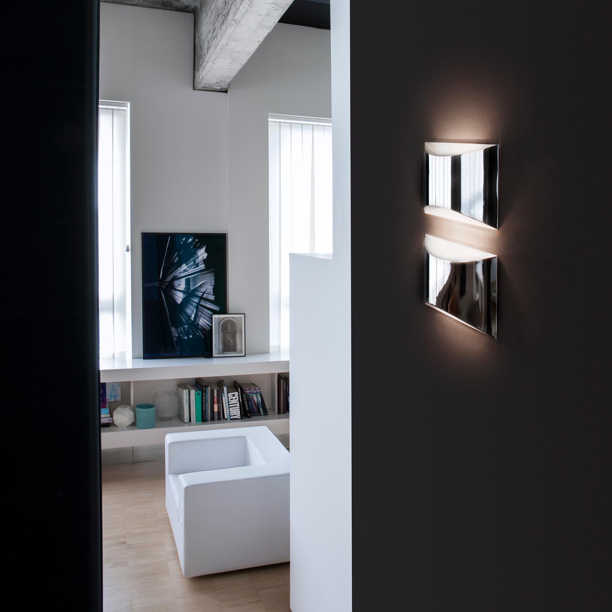 Wall lamp 'Kelly' designed by Design Studio 63 in 2011.
Wall lamp giving up & down light in curved laser-cut metal. White lacquered metal wall plate. White lacquered or chromium-plated metal screen. Manufactured by Oluce, Italy.

The Kelly wall lamp