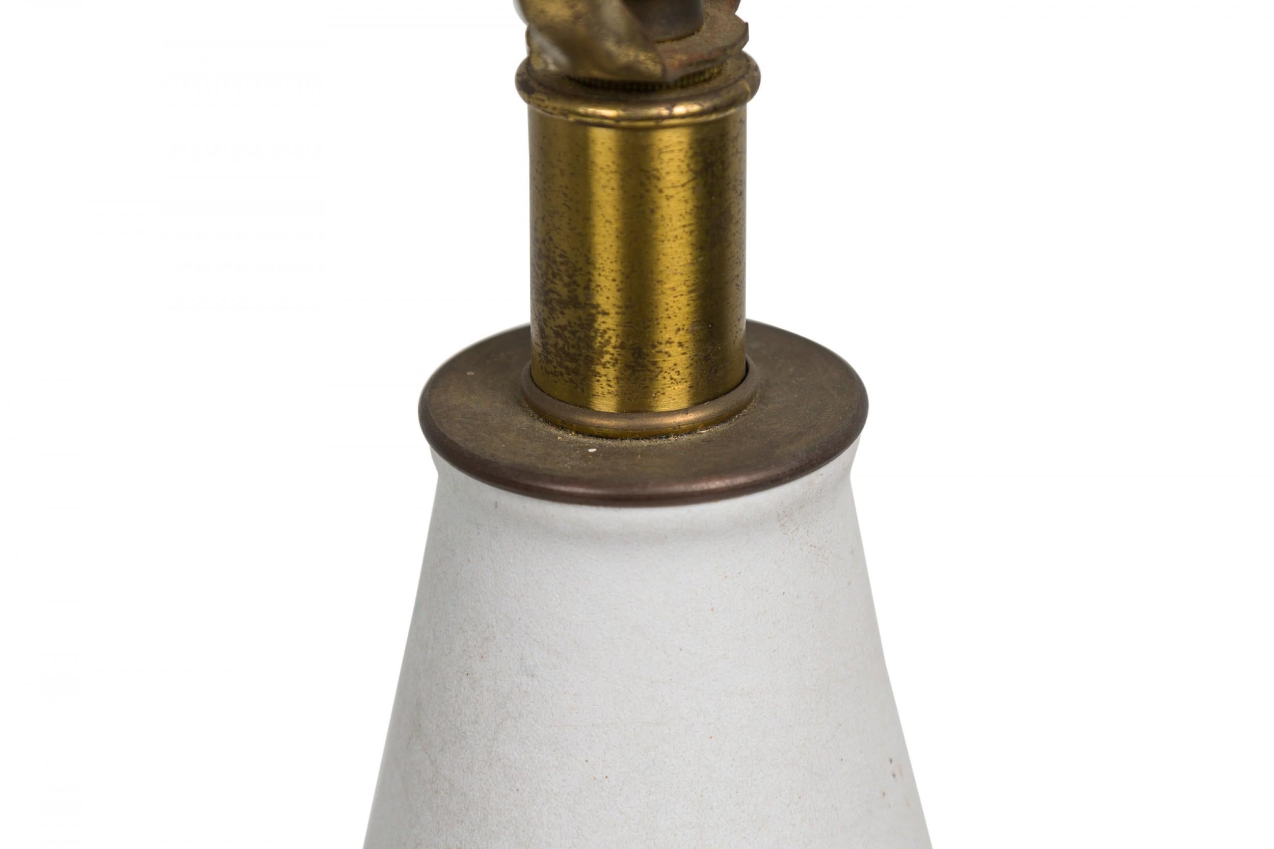 Mid-Century American ceramic table lamp in cylindrical form, tapering toward the top with a fitted brass functioning light switch, a heavily textured bark-like banded mid section ending in a tapered ring-footed bottom, fired in an opaque white matte