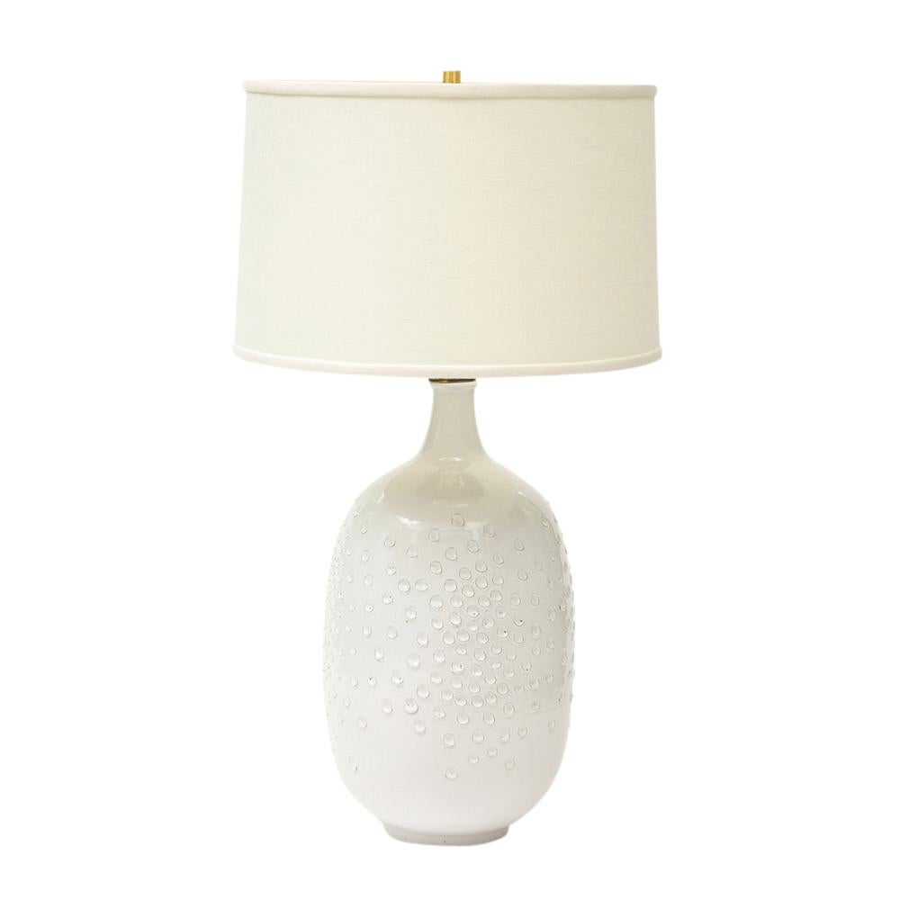 Design Technics lamp, pottery, white, dimpled, brass, signed. A hand-thrown stoneware table lamp glazed in white and decorated with a dimpled pattern. Retains original brass fittings and plastic cord. 3 way socket. Ceramic body measures 17.25 inches