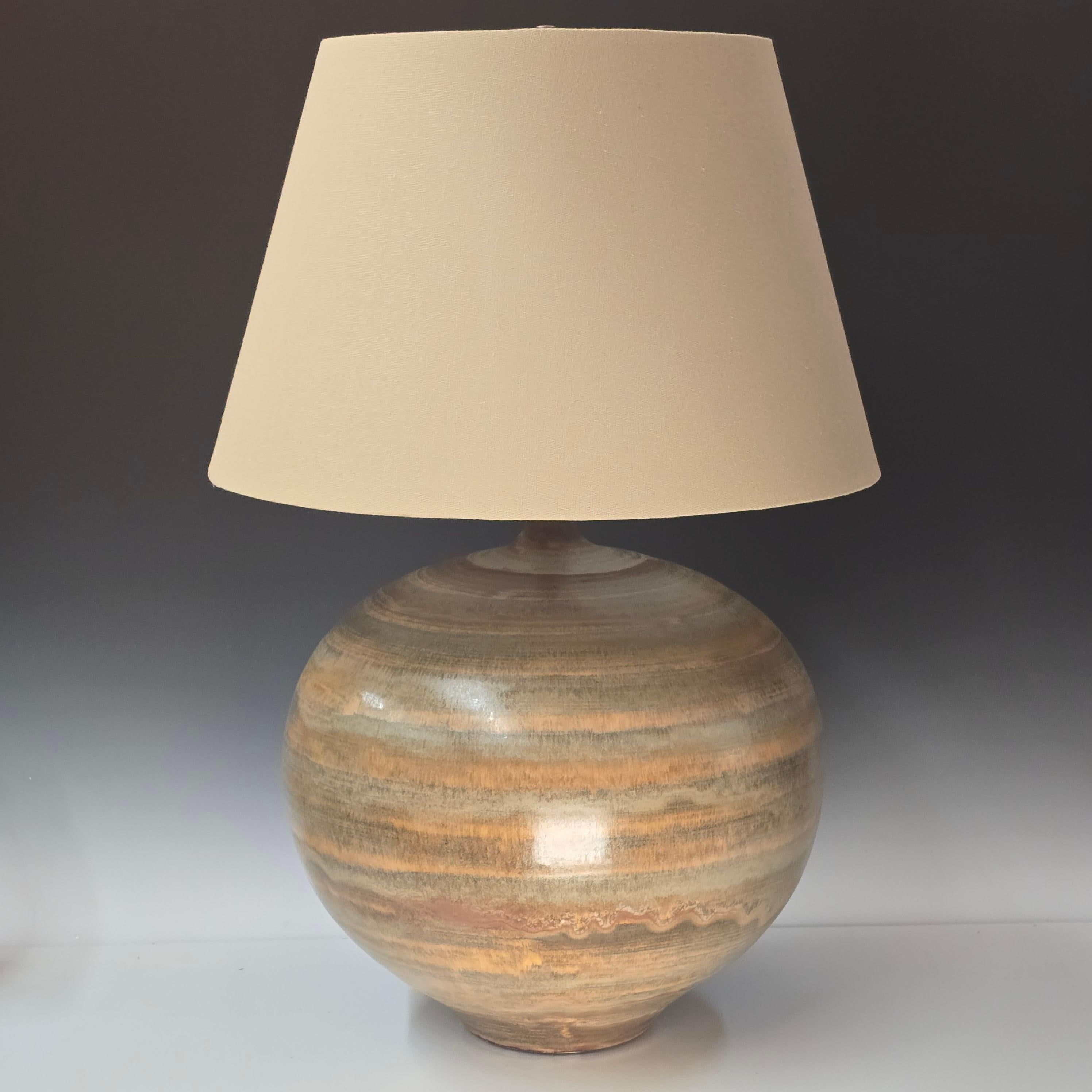A striking custom ordered extra large lamp with custom glaze mid-1950s Design Technics ceramic lamp, notable for its planetary, striated glaze that wraps the form in shifting bands of mineral green, sand, smoke, and rust. At 15 inches in diameter