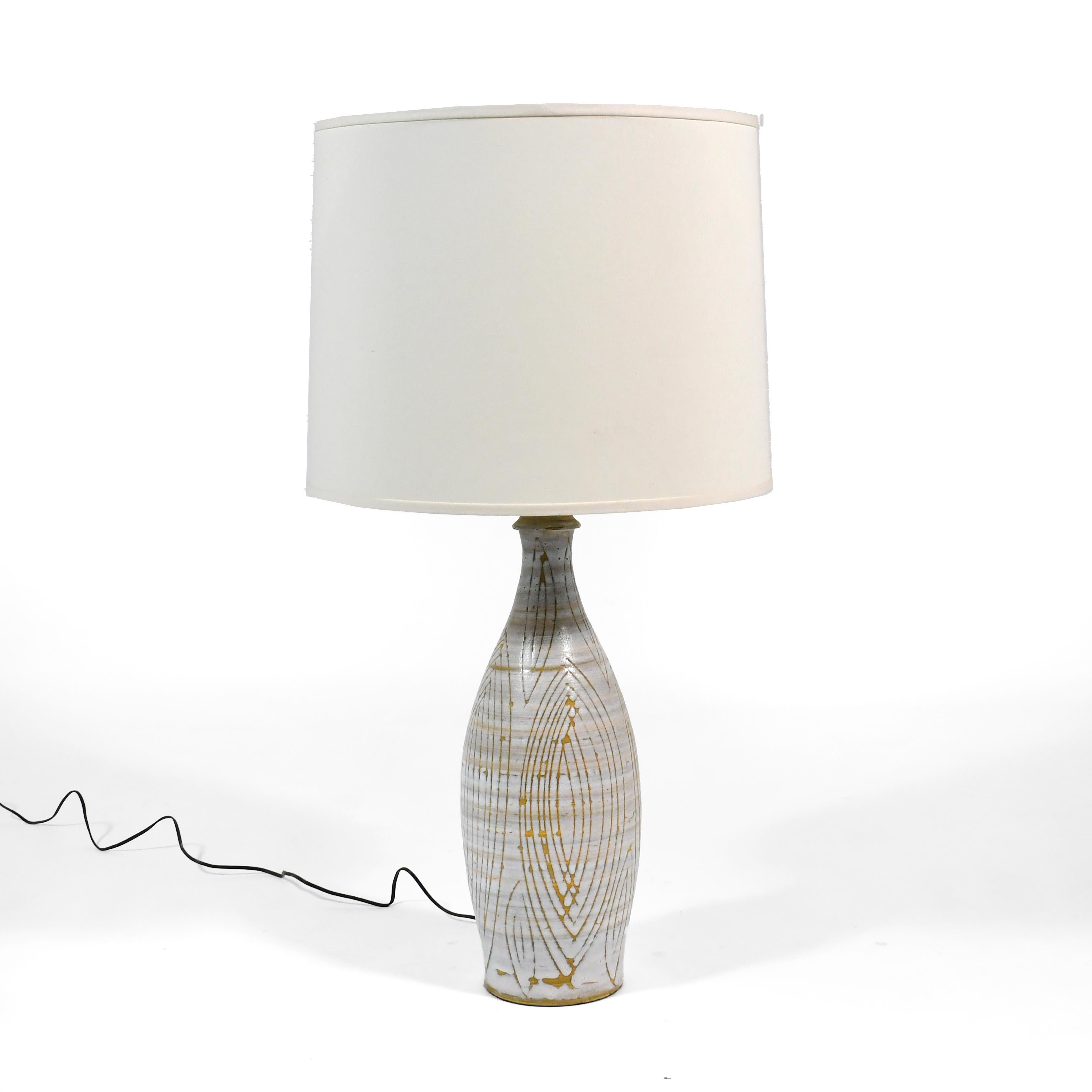 This strikingly beautiful lamp has a base of ceramic decorated with a ivory glaze that has an all-over sgraffito design. The combination of the shape of the lamp body and the hand-applied pattern makes the subtle elements work together to great