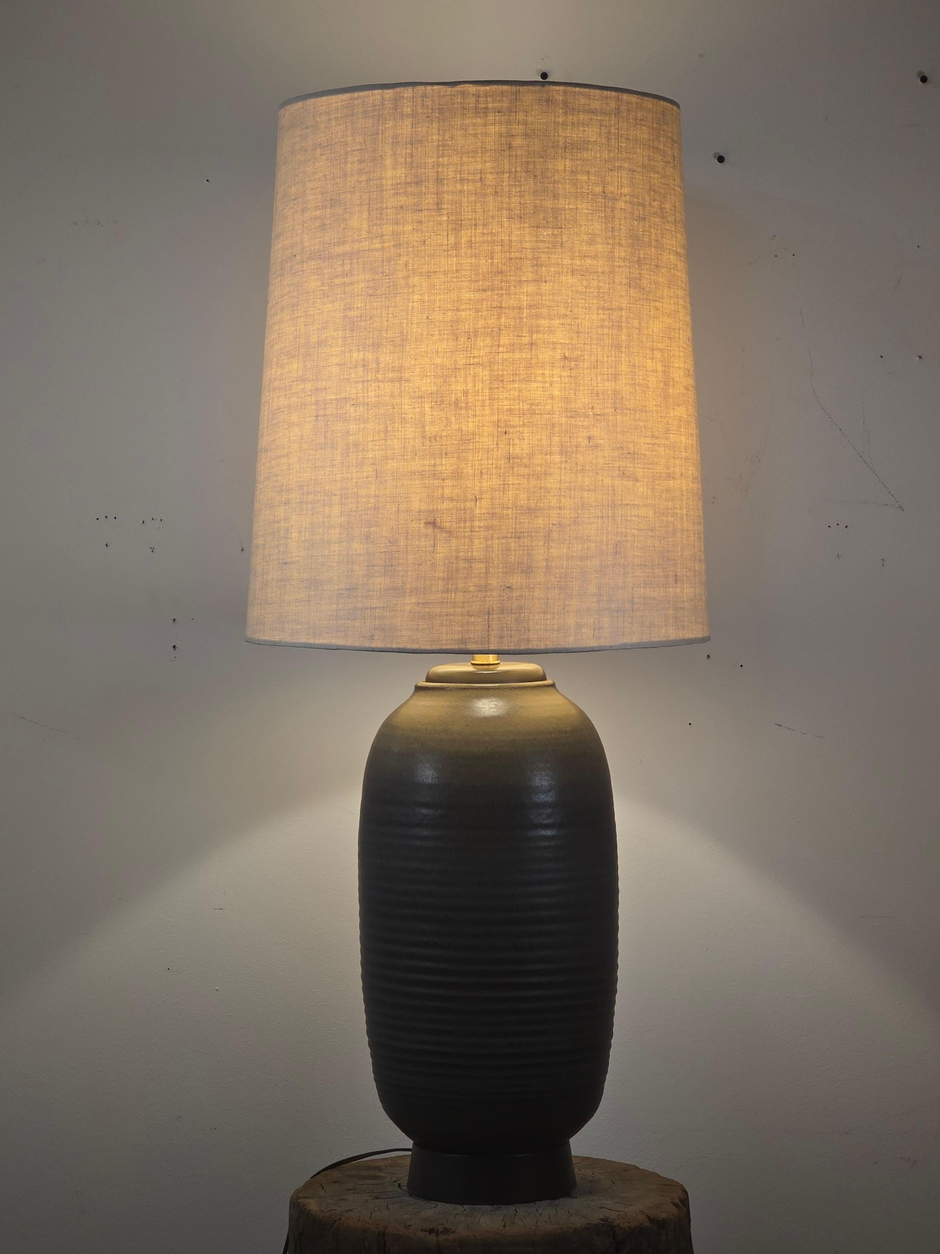 A striking mid-century ceramic table lamp by Design Technics, featuring a tall ribbed body finished in their distinctive KT matte glaze. The form is capped with a walnut neck and rests on a flared walnut base, creating a warm contrast to the cool,