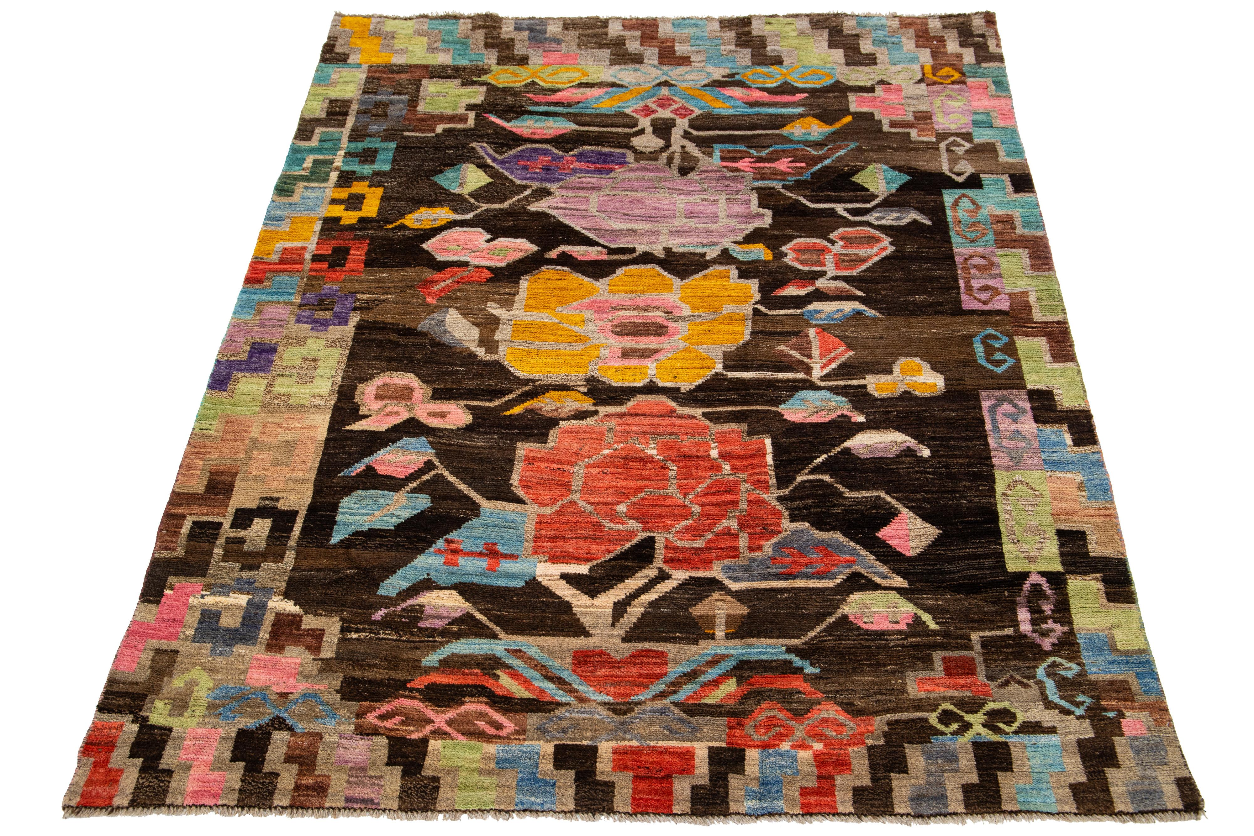 Ce tapis contemporain en laine de style marocain présente un champ de couleur marron captivant avec des fleurs multicolores façonnées dans un motif all-over.

Ce tapis mesure 5'8