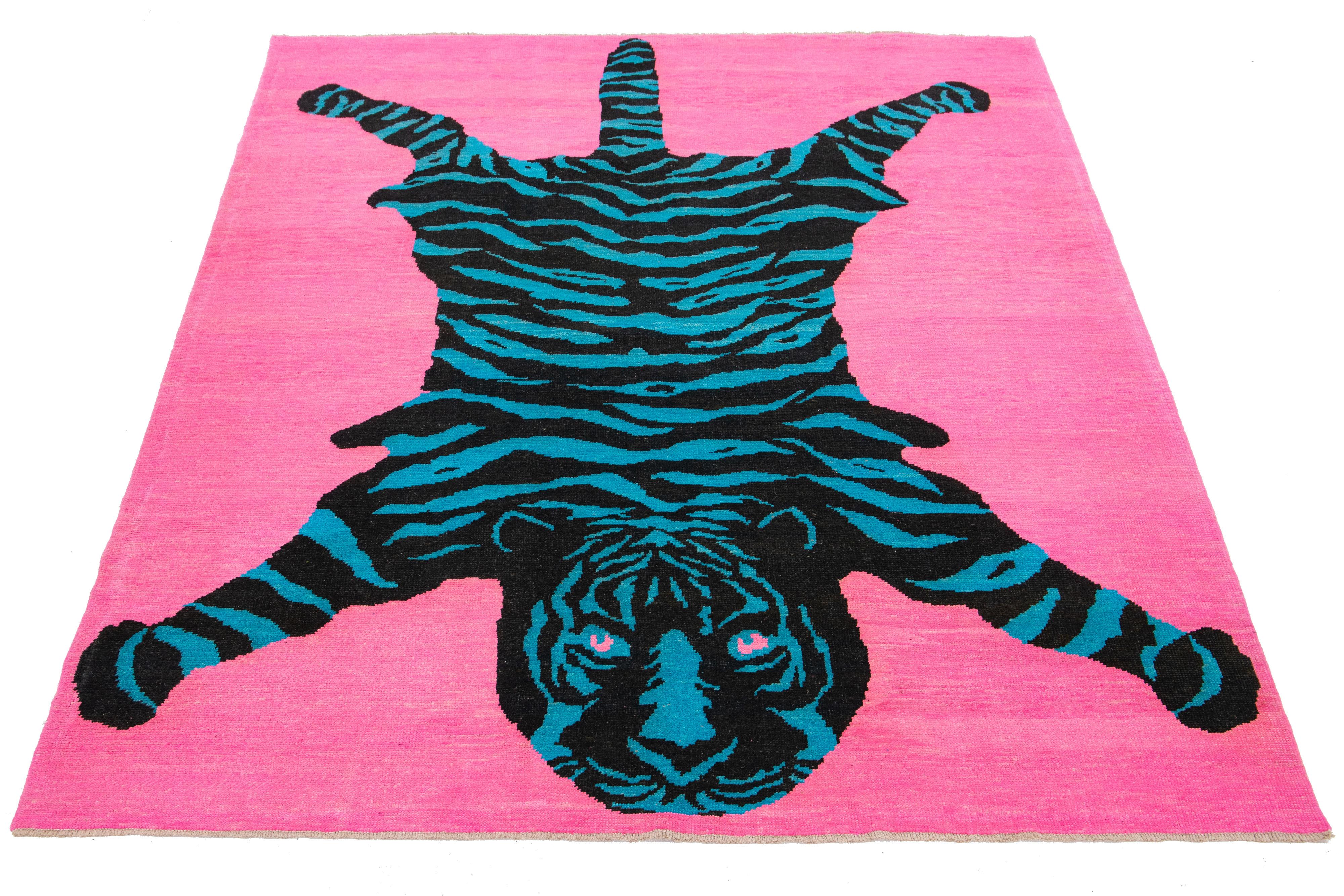 This Turkish room-size wool rug features a beautiful tiger pictorial design with a pink field and black and blue accent colors. It is handmade with care.

This rug measures 8' x 10'8