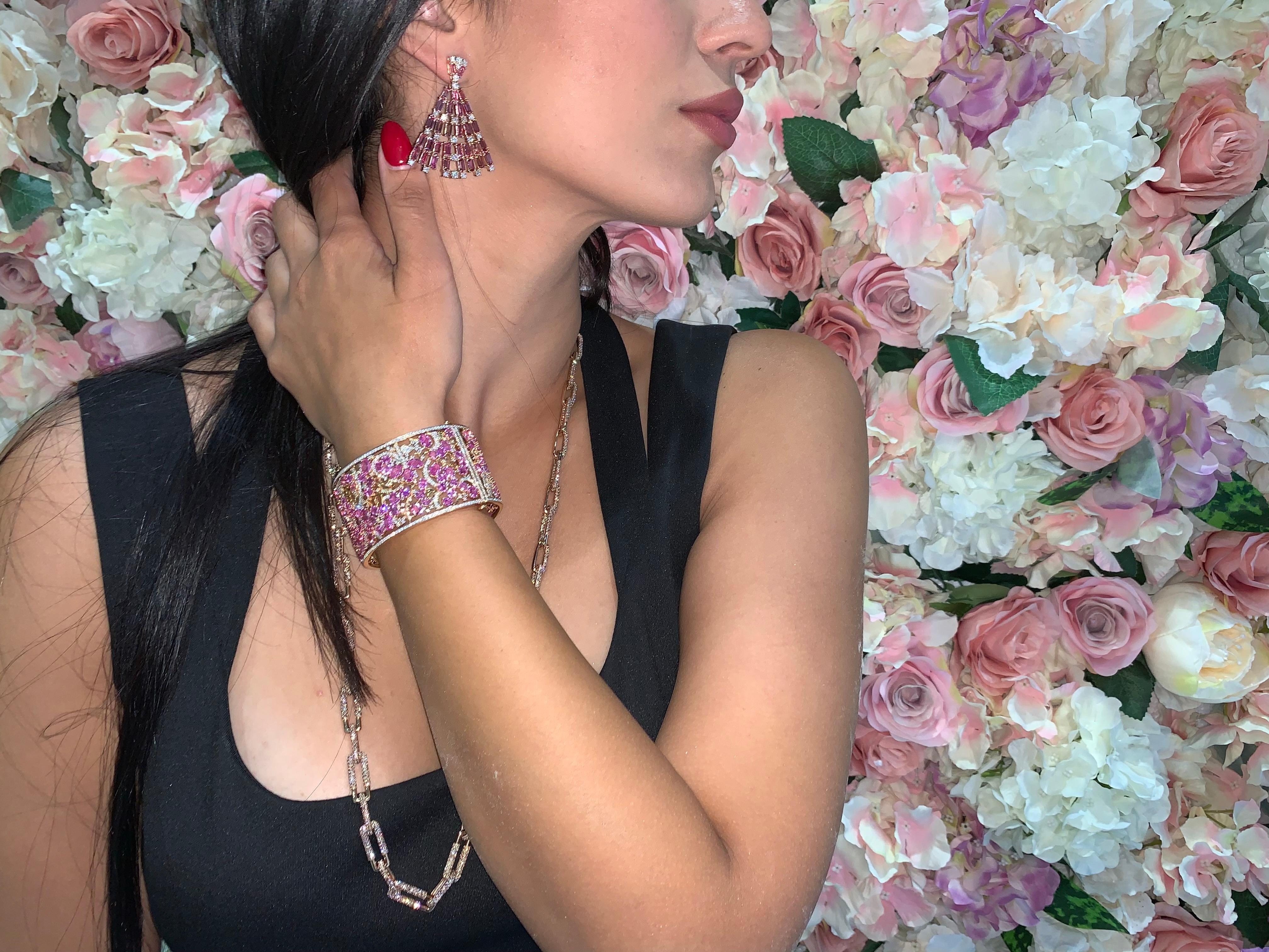 Sunita Nahata präsentiert ein exklusives Designerarmband, das mit rosa Saphiren und Diamanten verziert ist. Die Edelsteine sind so gefasst, dass sie die rosa Blüten elegant zur Geltung bringen, während die detaillierte Goldarbeit die stützenden